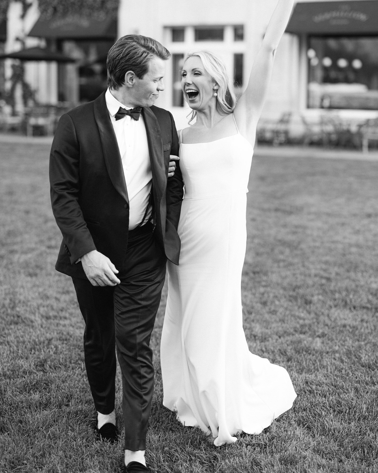 A radiant elopement photograph capturing a joyful celebration on the Banff Springs Hotel lawn in Banff National Park. Holding hands, the bride raises her arm in pure happiness, embracing the excitement and beauty of their unforgettable wedding day in the heart of the Canadian Rockies.