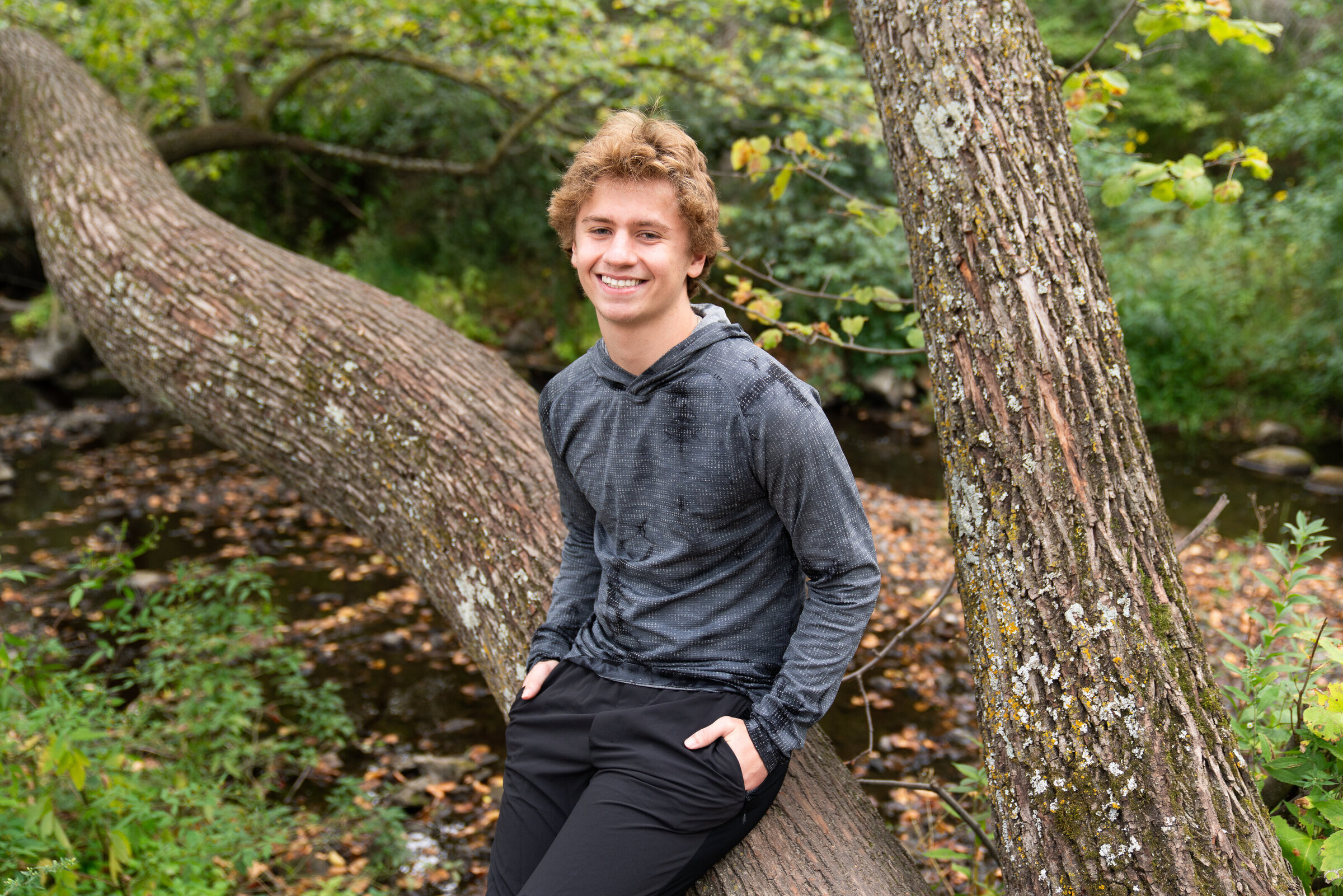 Guy leans against a tree during his senior photo shoot
