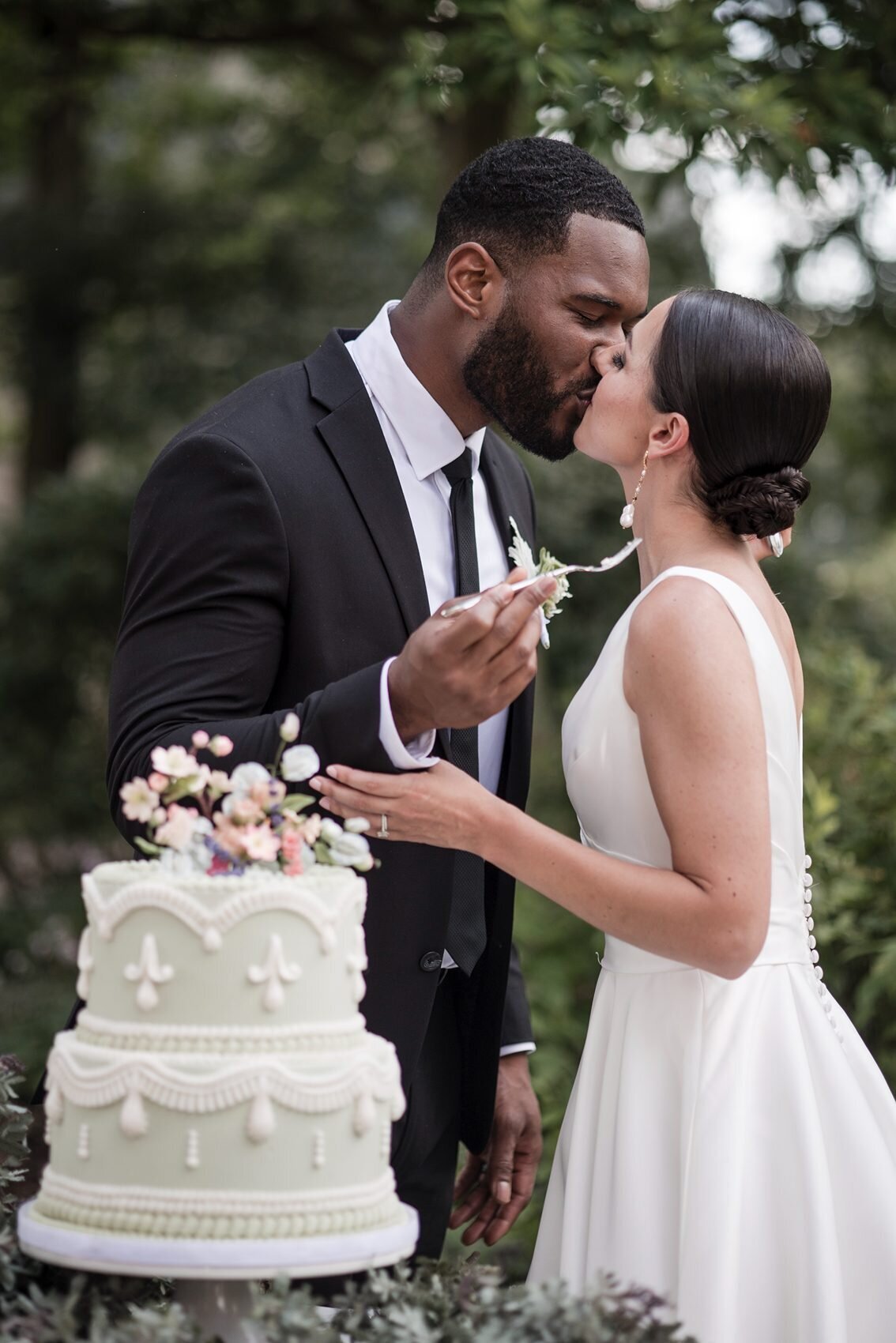 Elegant interracial wedding couple kissing after feeding each other from the beautiful cake cutting.