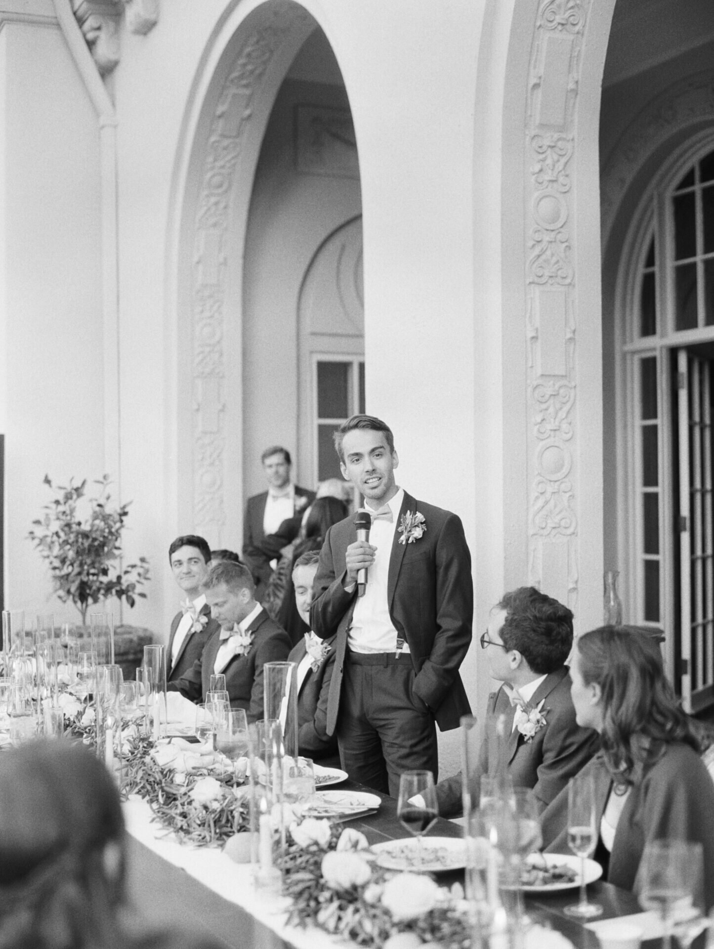 black and white film photo of best man giving speech at wedding reception