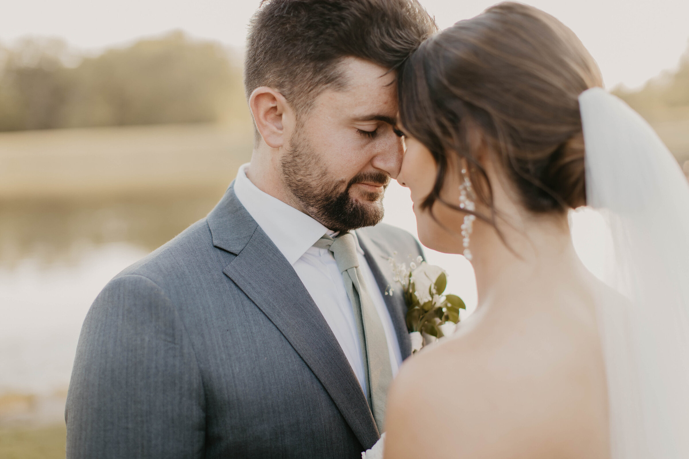 Bride and groom standing with forehead together. 