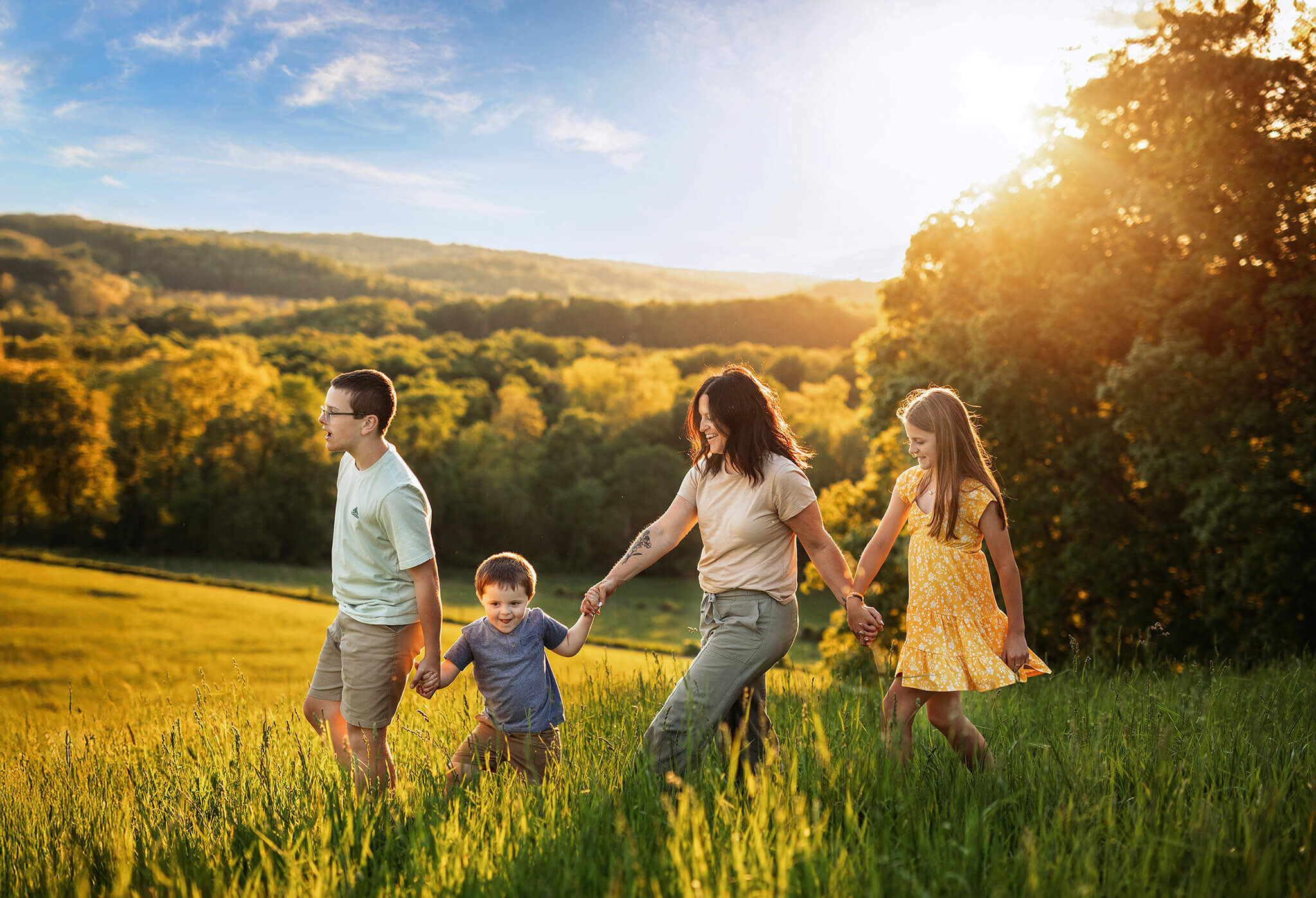 Mother with her 3 children holding hands walking on hill