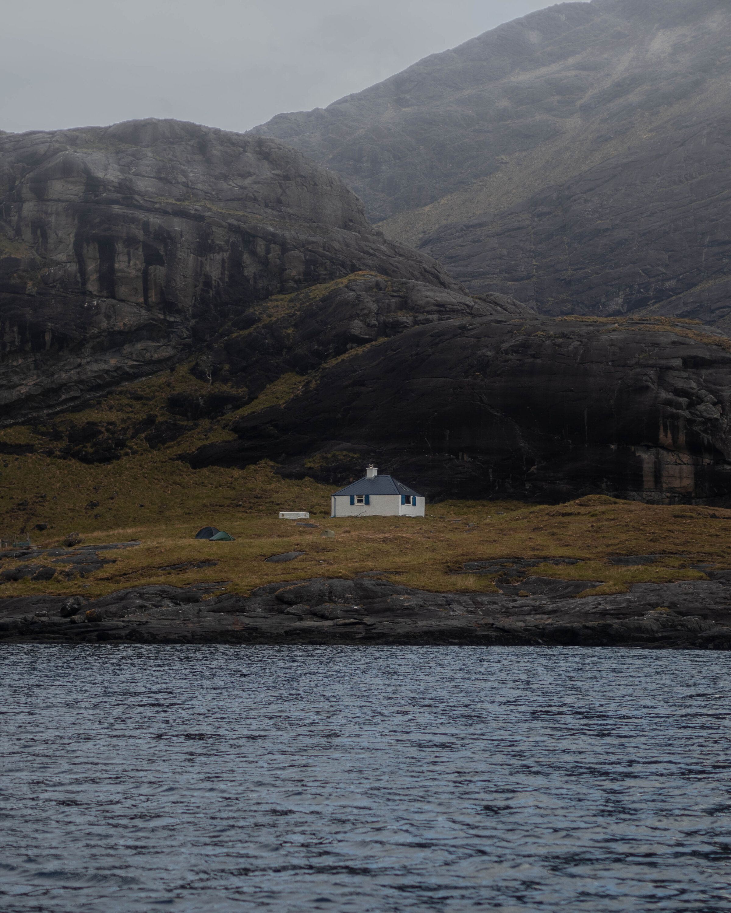 small house on stony isolated island with dark blue ocean surrounding the island