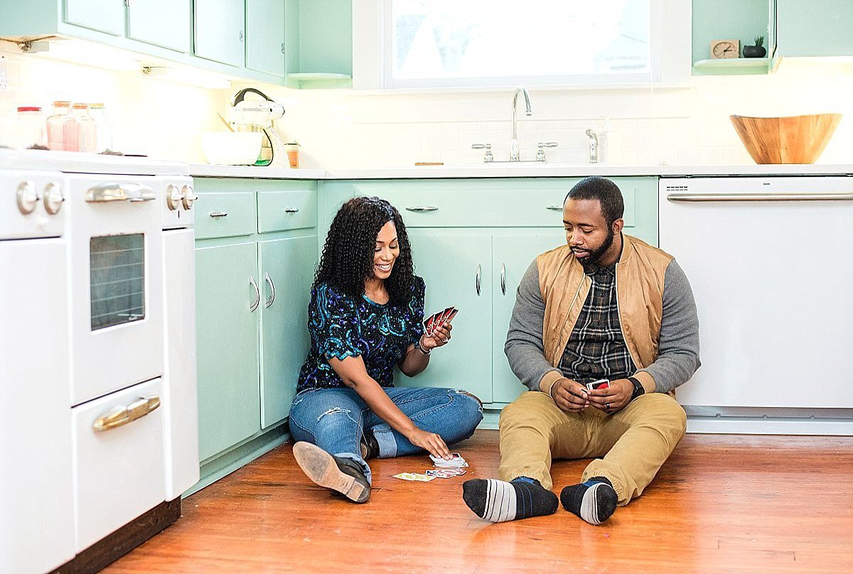 Social media influencers Love At Any Stage sitting on retro kitchen floor playing cards together