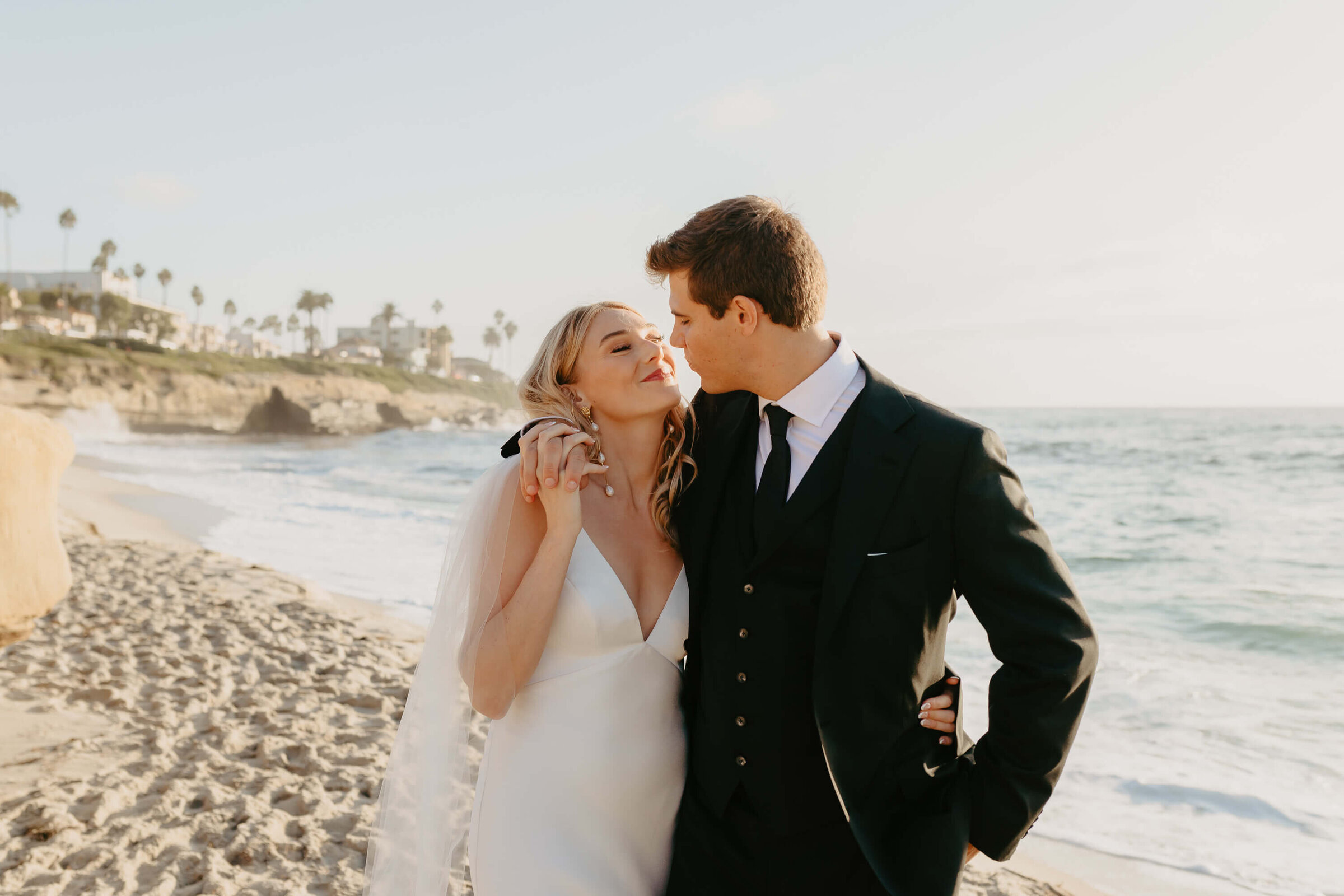 Elegant Hollywood couple kissing on a La Jolla beach