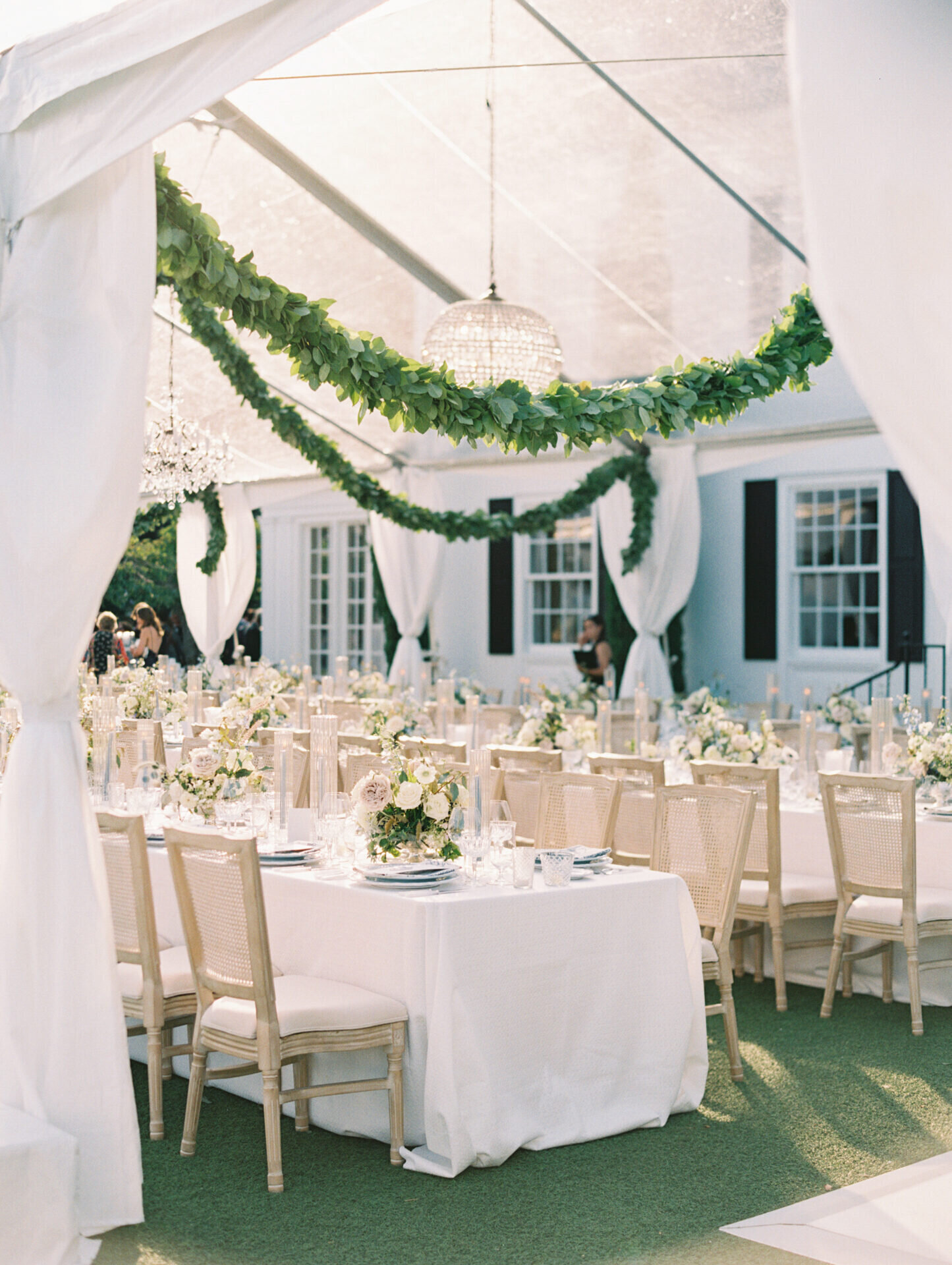 green garland hanging above white wedding tables on green grass at the admiral's house