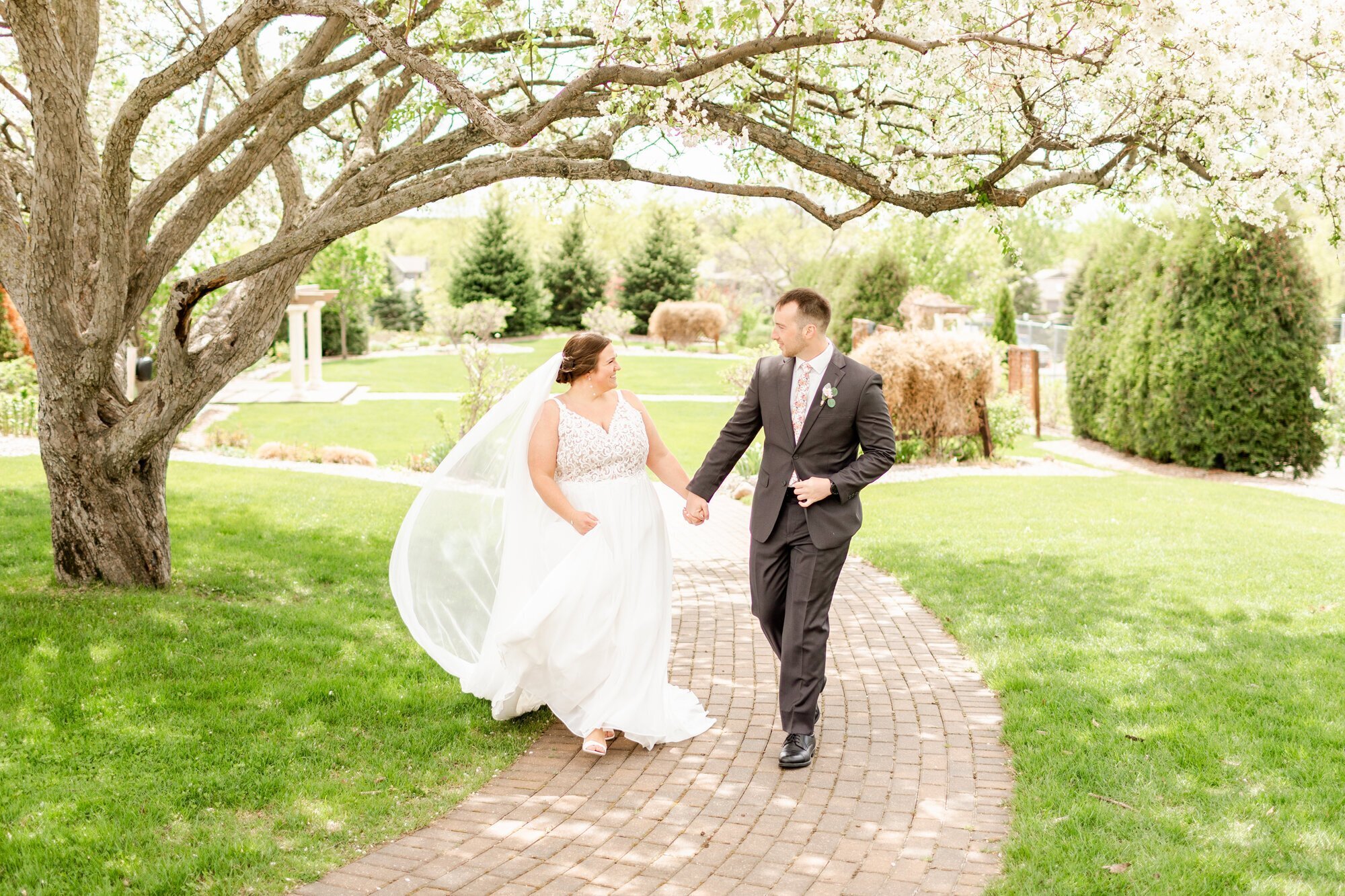 Bride and groom holding hands and walking on a path, taken by wedding photographers in minneapolis