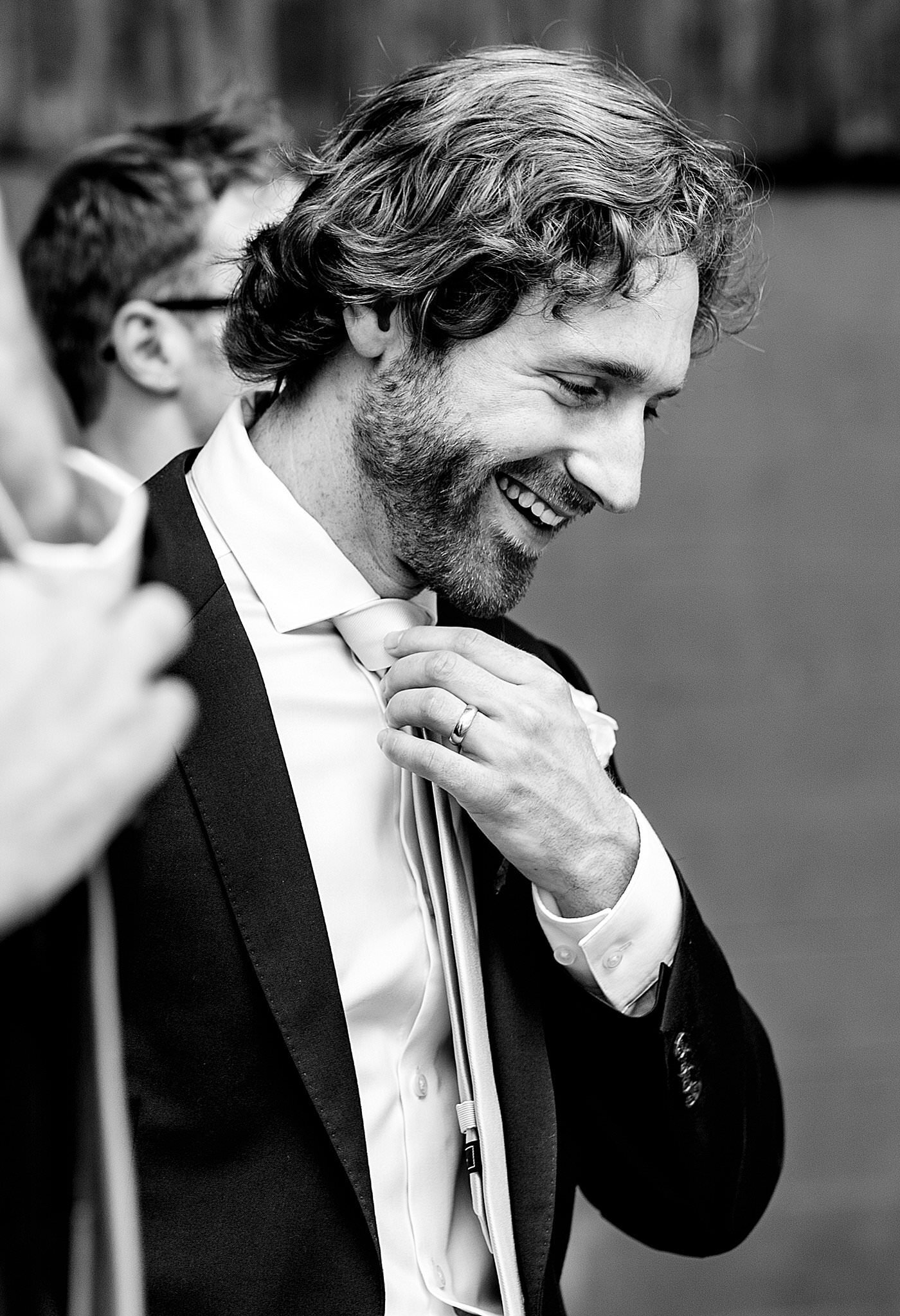 Black and white photo of groom adjusting his tie