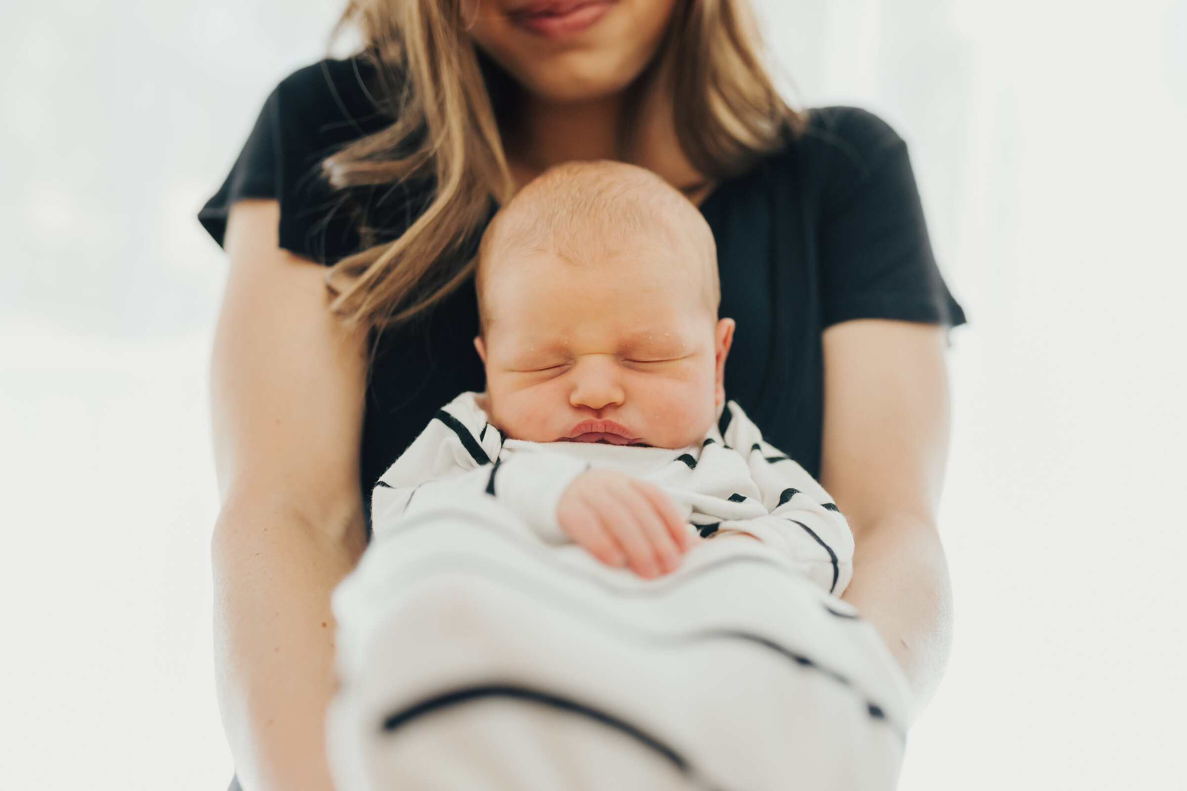 Newborn sleeps and is held by mom on her chest