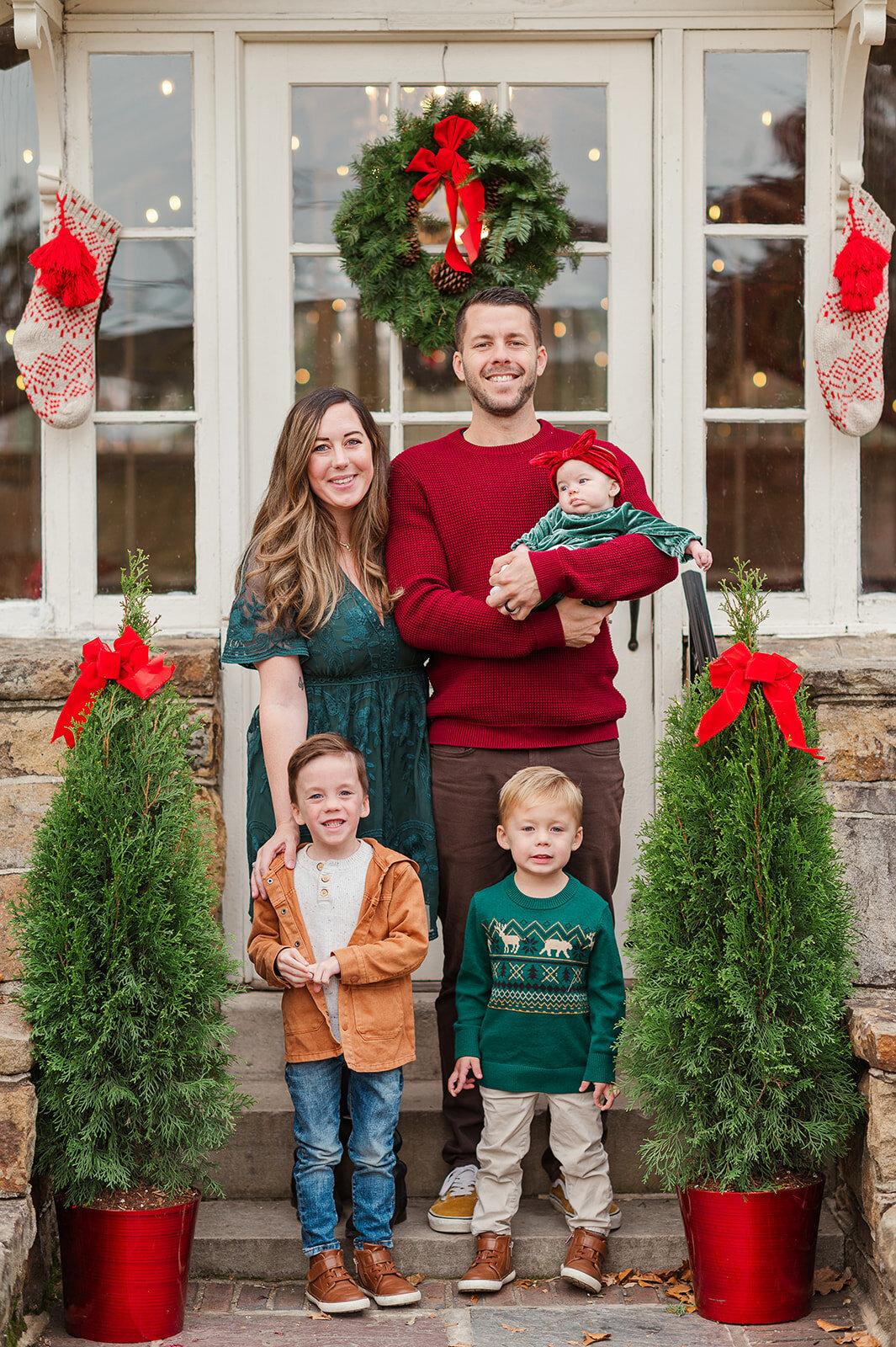  Family dressed in festive colors posing on decorated porch during Christmas mini session in Lancaster, PA