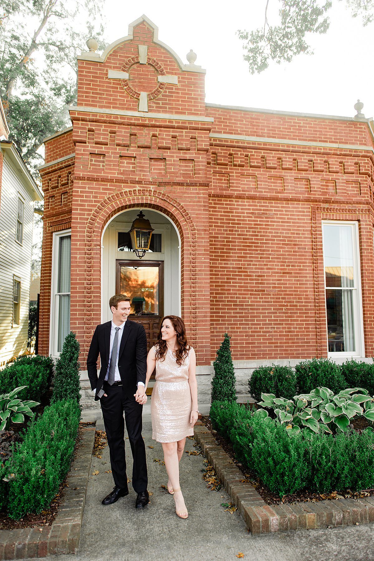 Girl wearing rose gold sequin dress and black suit in front of a historic building in downtown Franklin