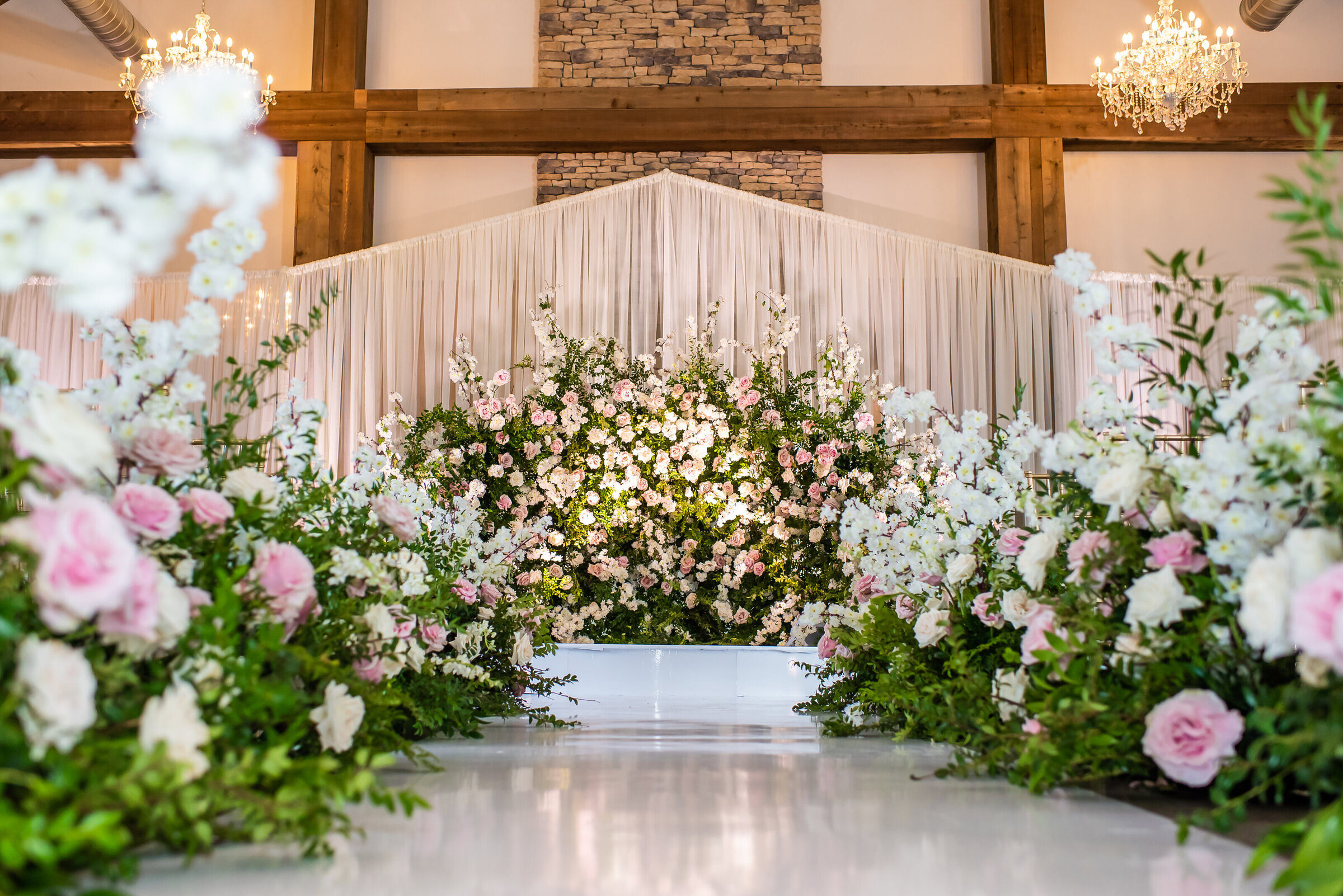 Romantic floral aisle with pink, blush, and white garden-style arrangements leading to a luxurious altar, captured at a Birmingham wedding by Wells Design Co