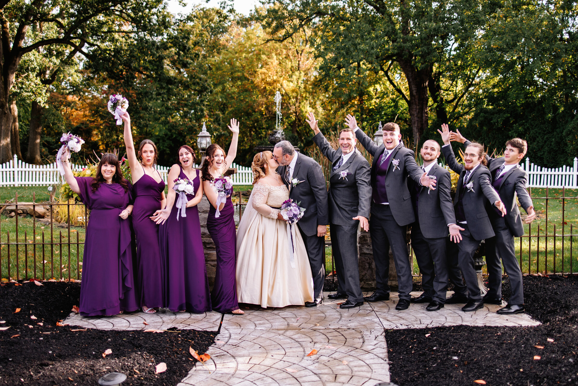 Bridal party cheers enthusiastically while bride and groom share a kiss