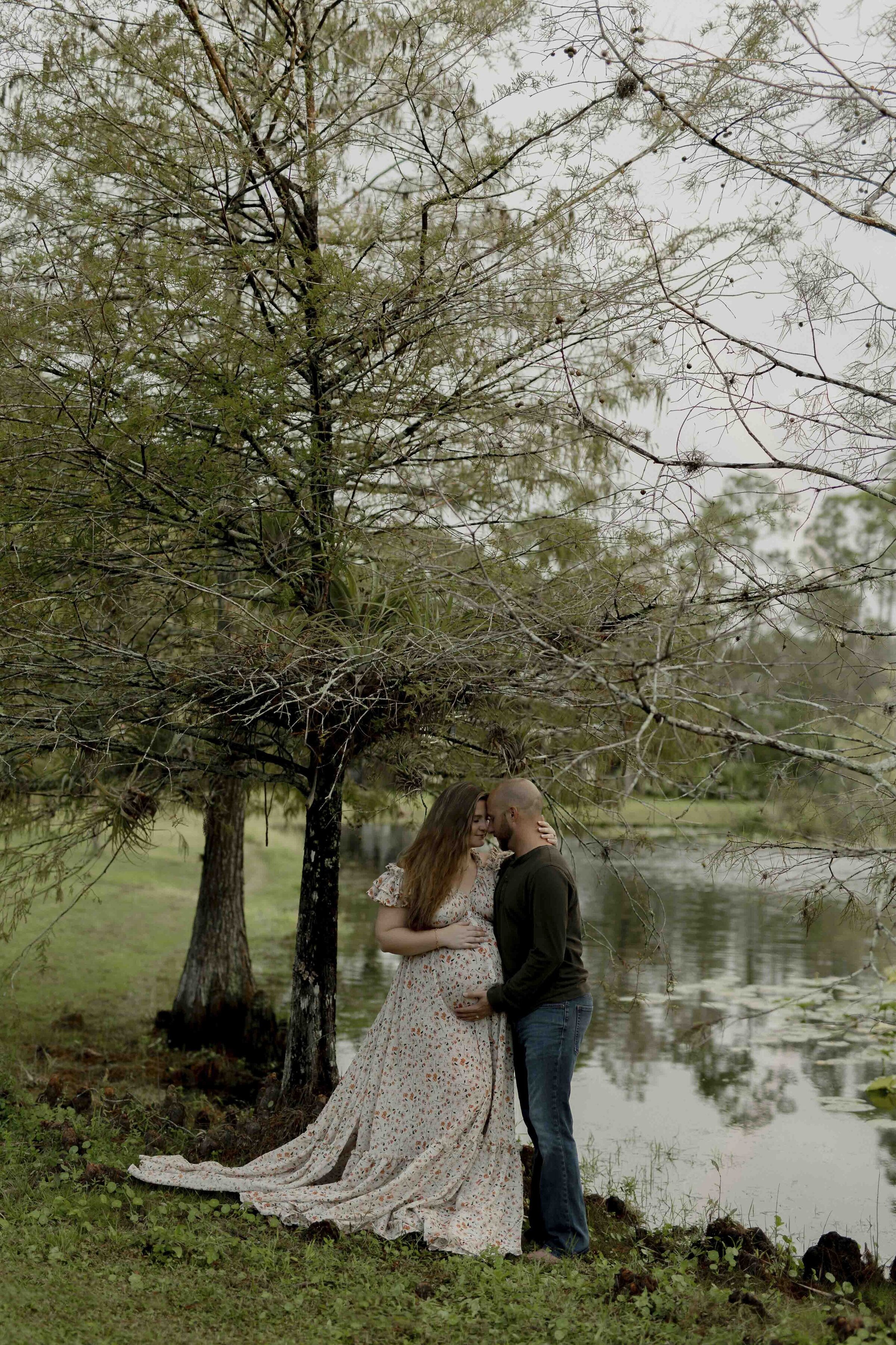 Pregnant couple embracing by a lake