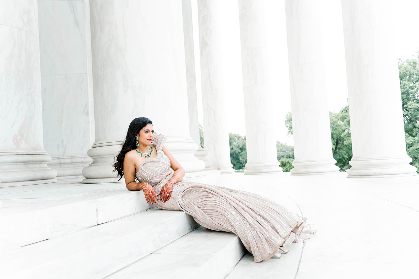 Elegant South Asian bride in a champagne Gaurav Gupta lehenga posing on the marble steps of the Jefferson Memorial in Washington DC, captured by Mari Harsan Studios.