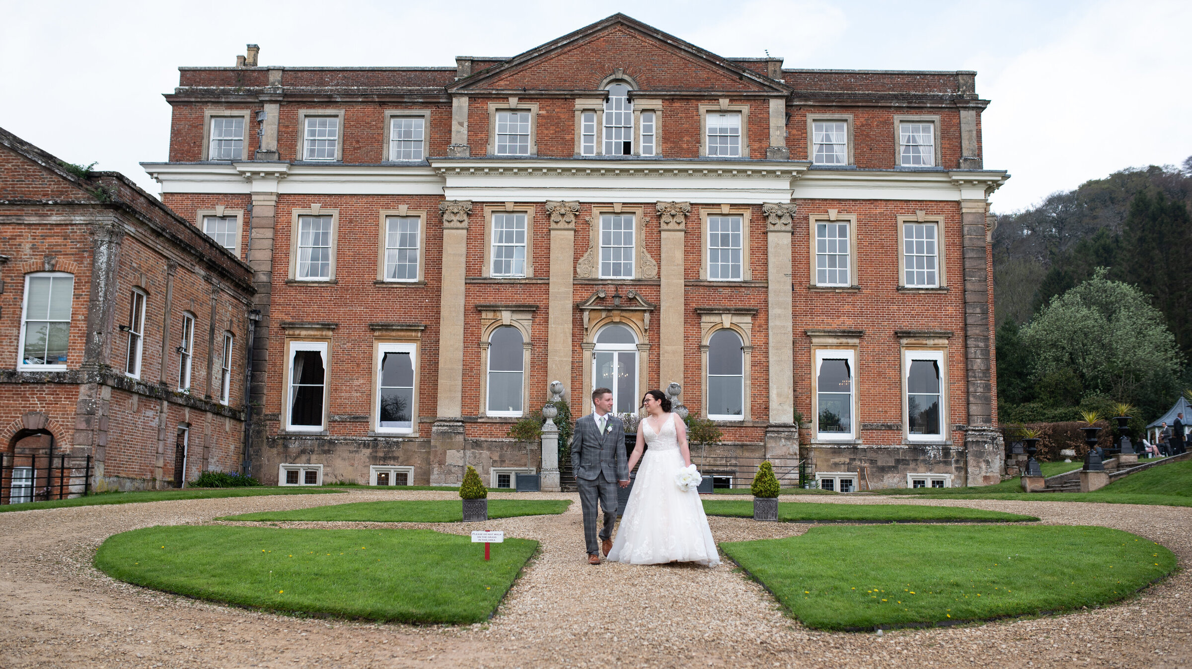 Bride and Groom in wedding attire walking together holding hands in front of Crowcombe Court wedding venue
