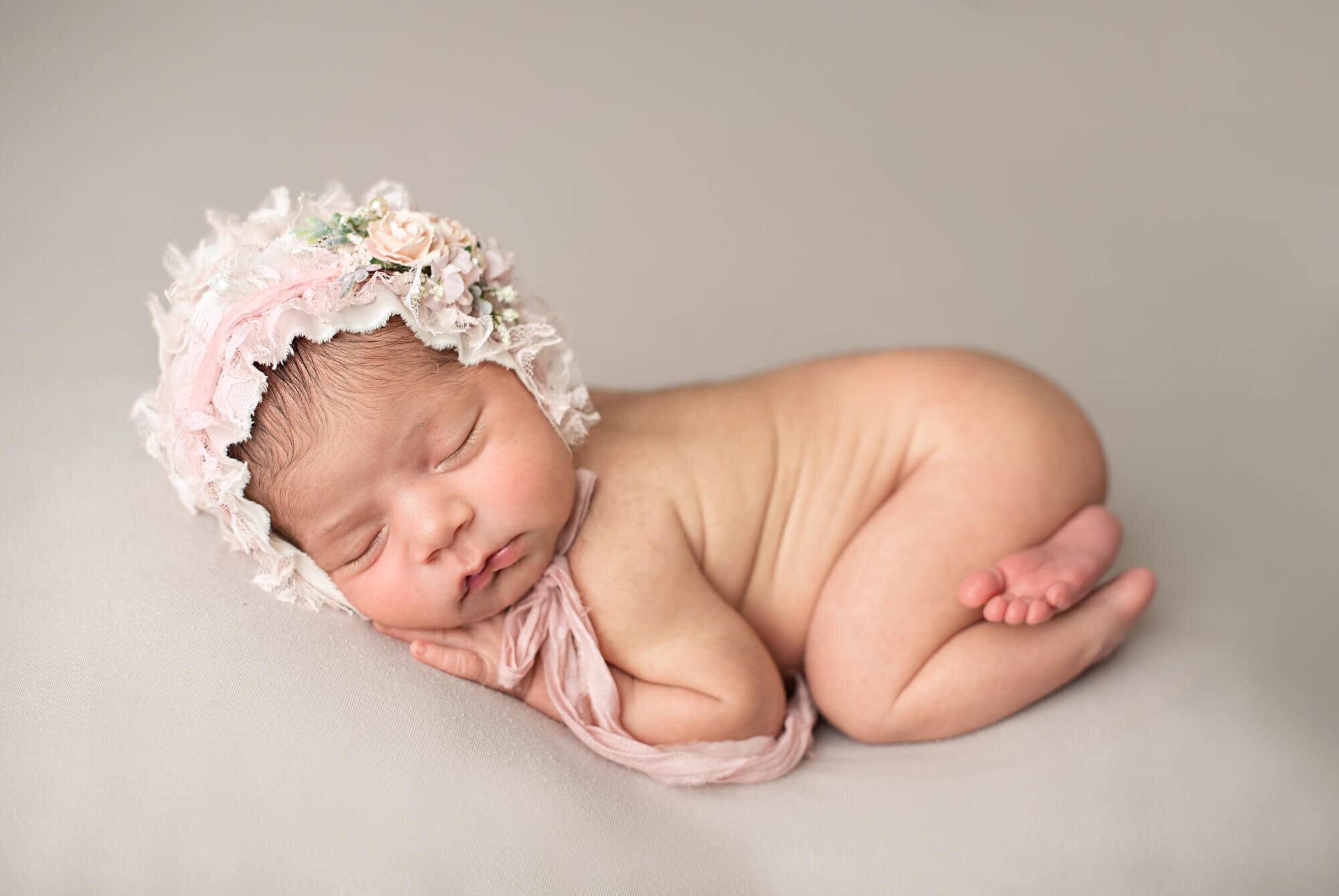 Sleeping newborn girl with pink bonnet
