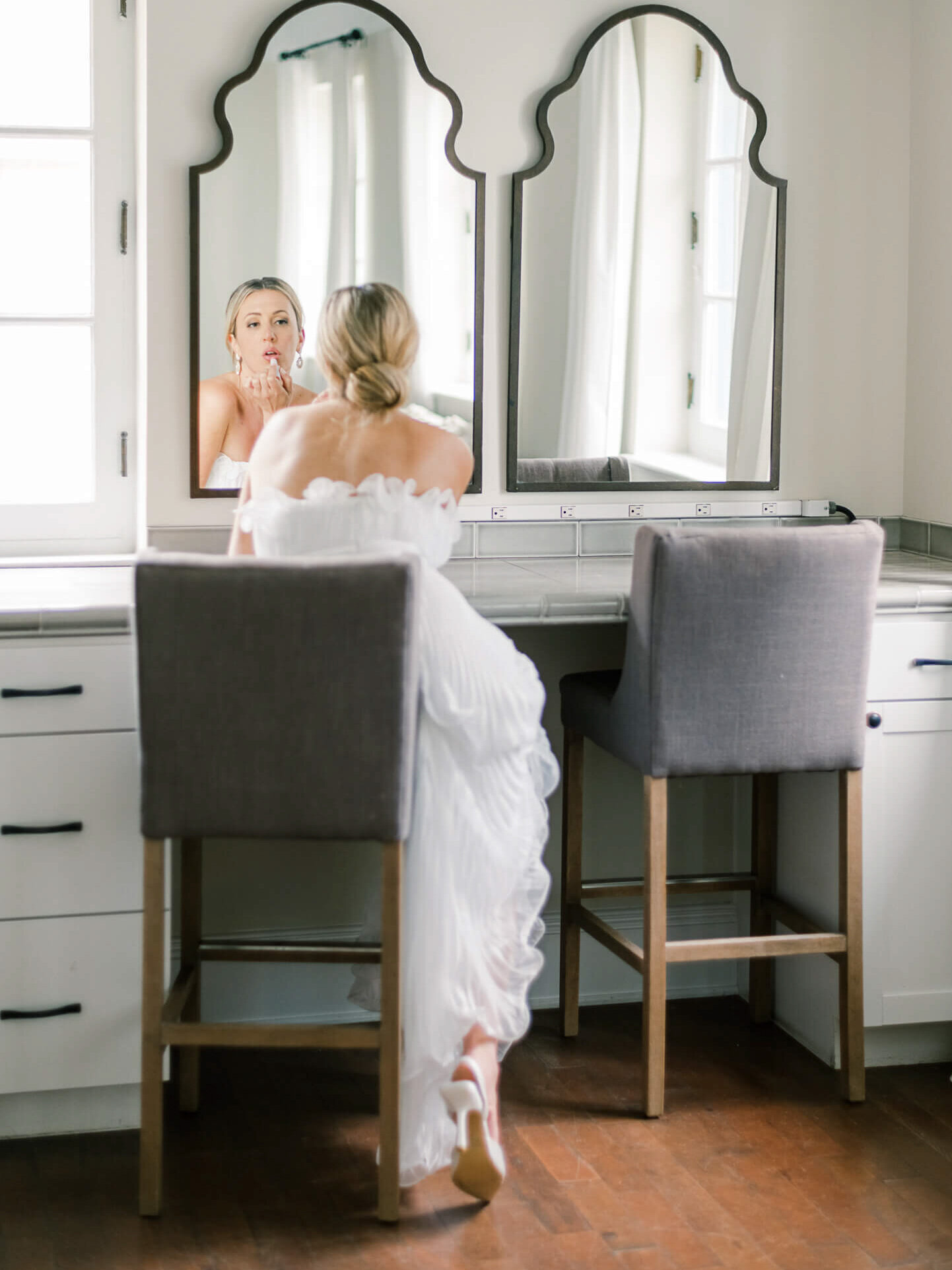Bride looking in mirror putting on lipstick