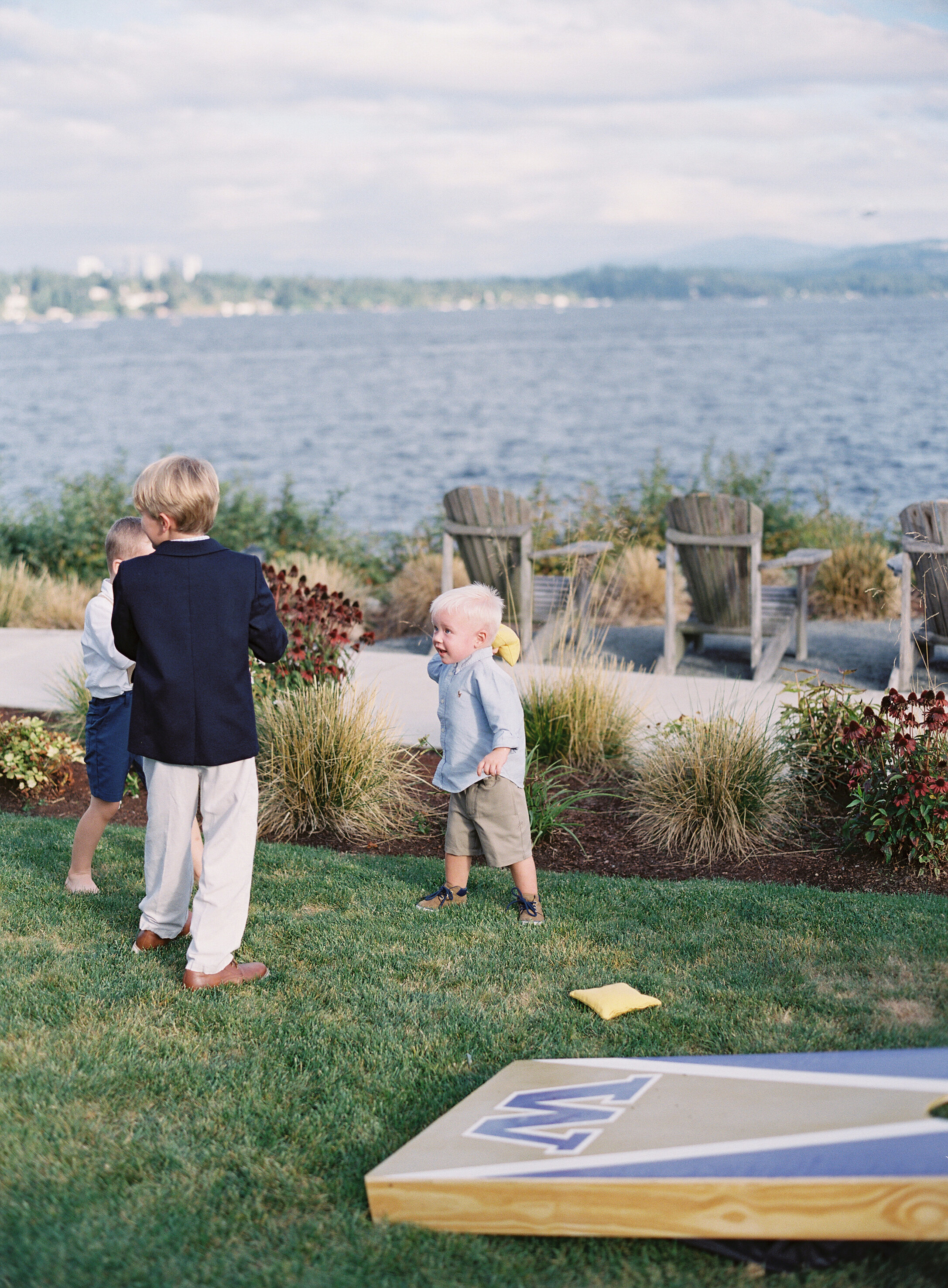 kids play near the bean bag toss at lake front wedding cocktail hour