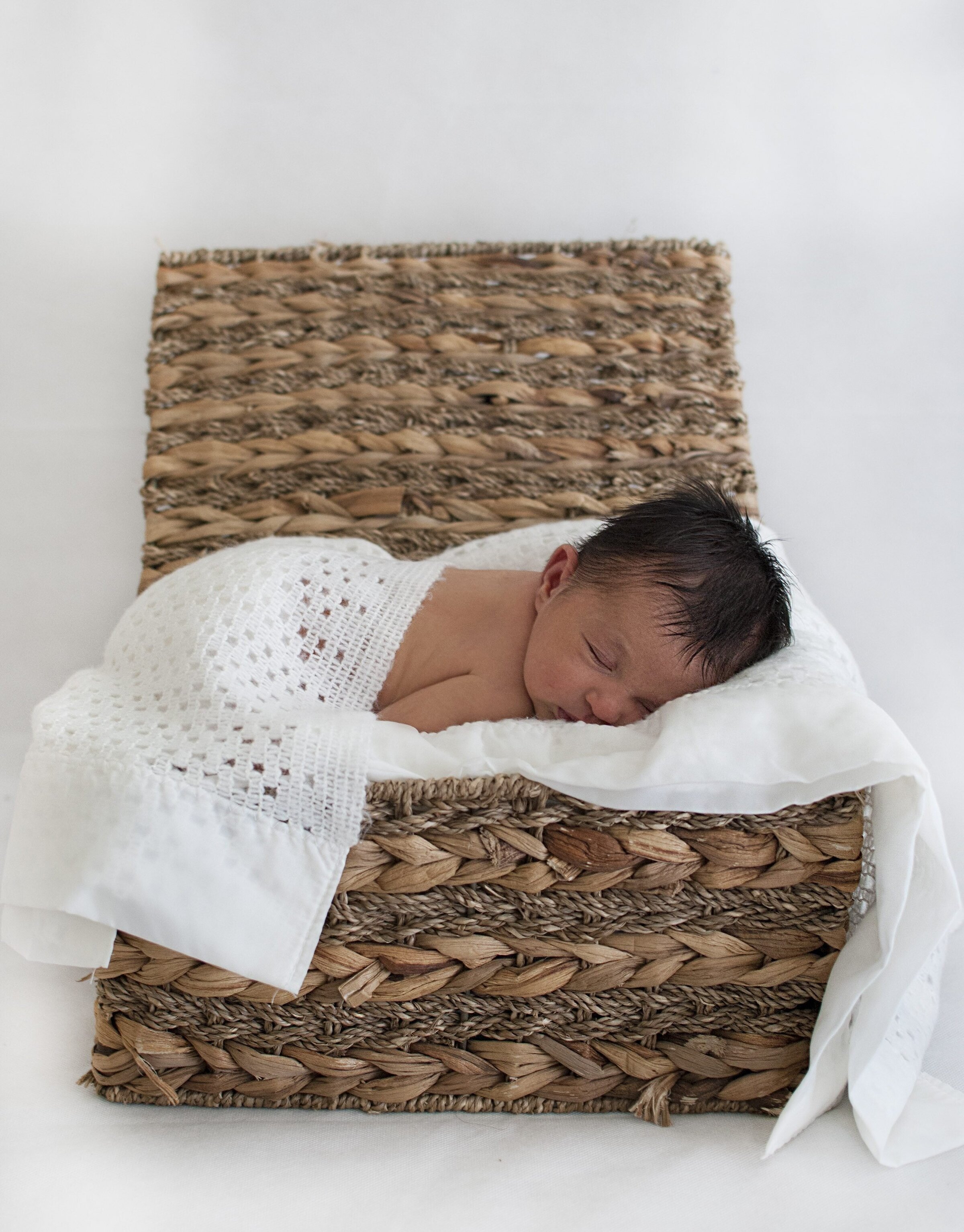 Newborn baby sleeping in a wicker basket
