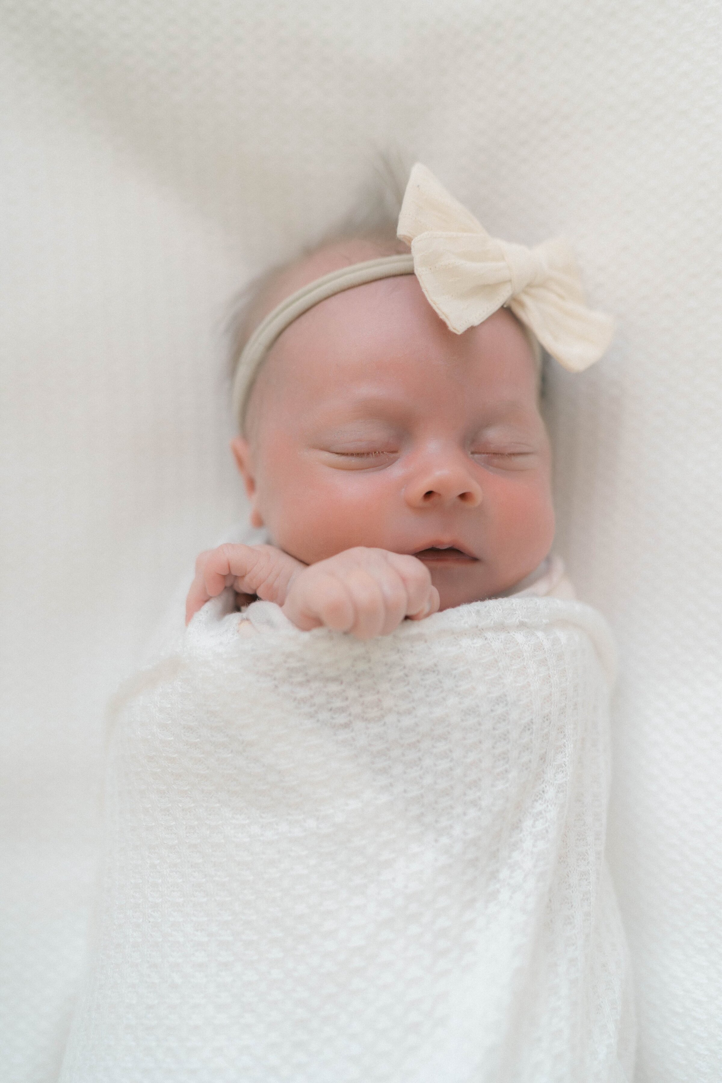 Newborn baby wrapped and sleeping on a bed with an airy, organic aesthetic by a Utah Newborn Photographer.