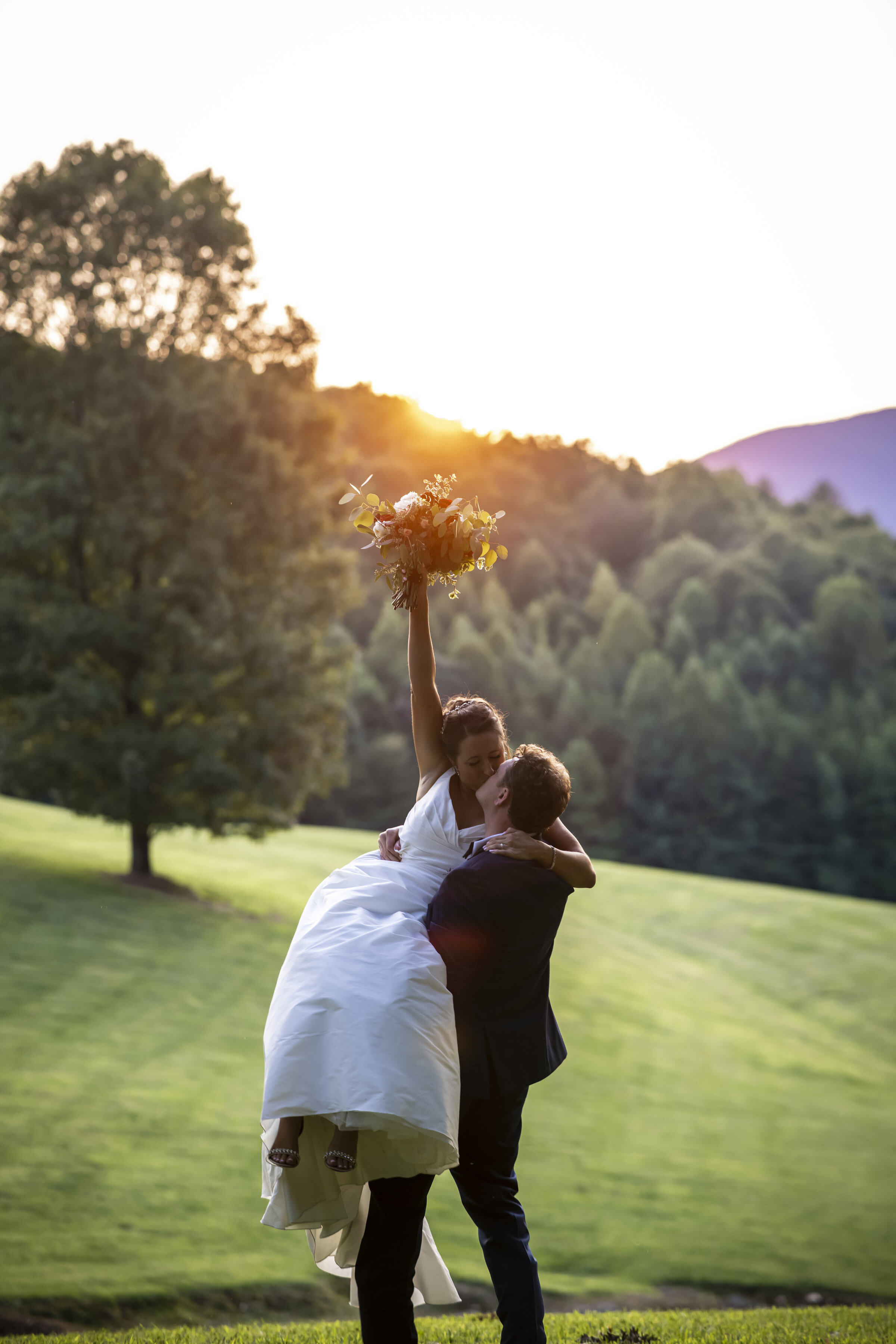 Groom holding bride in air and kissing her.