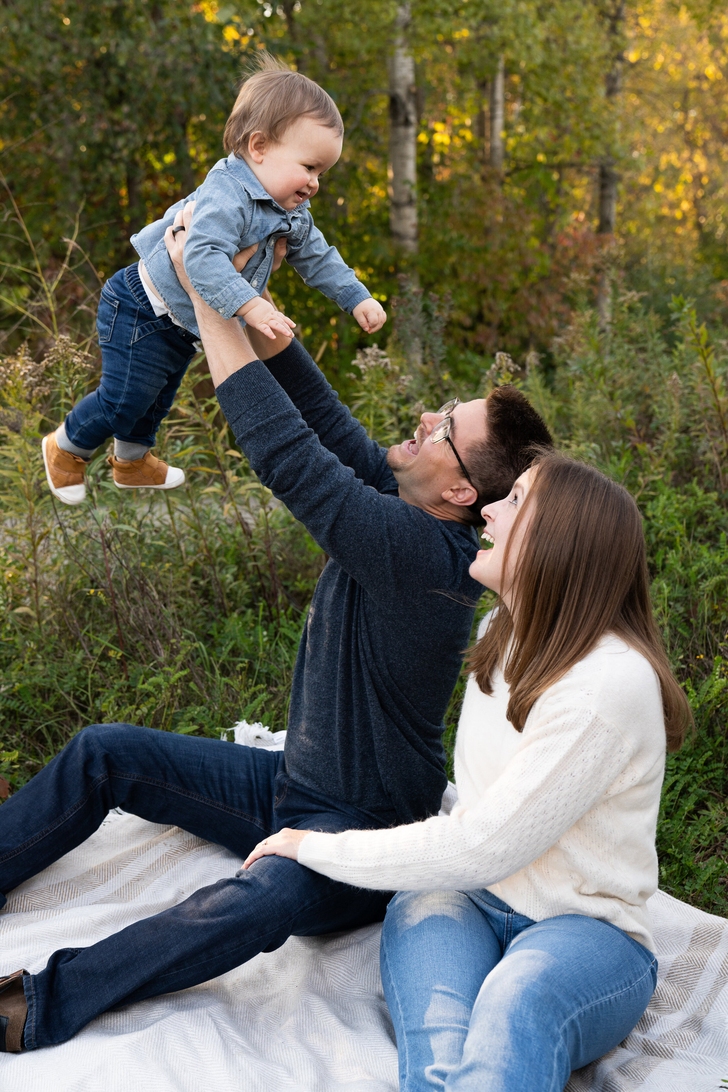 A father lifts his son up in the air during a family photo shoot.