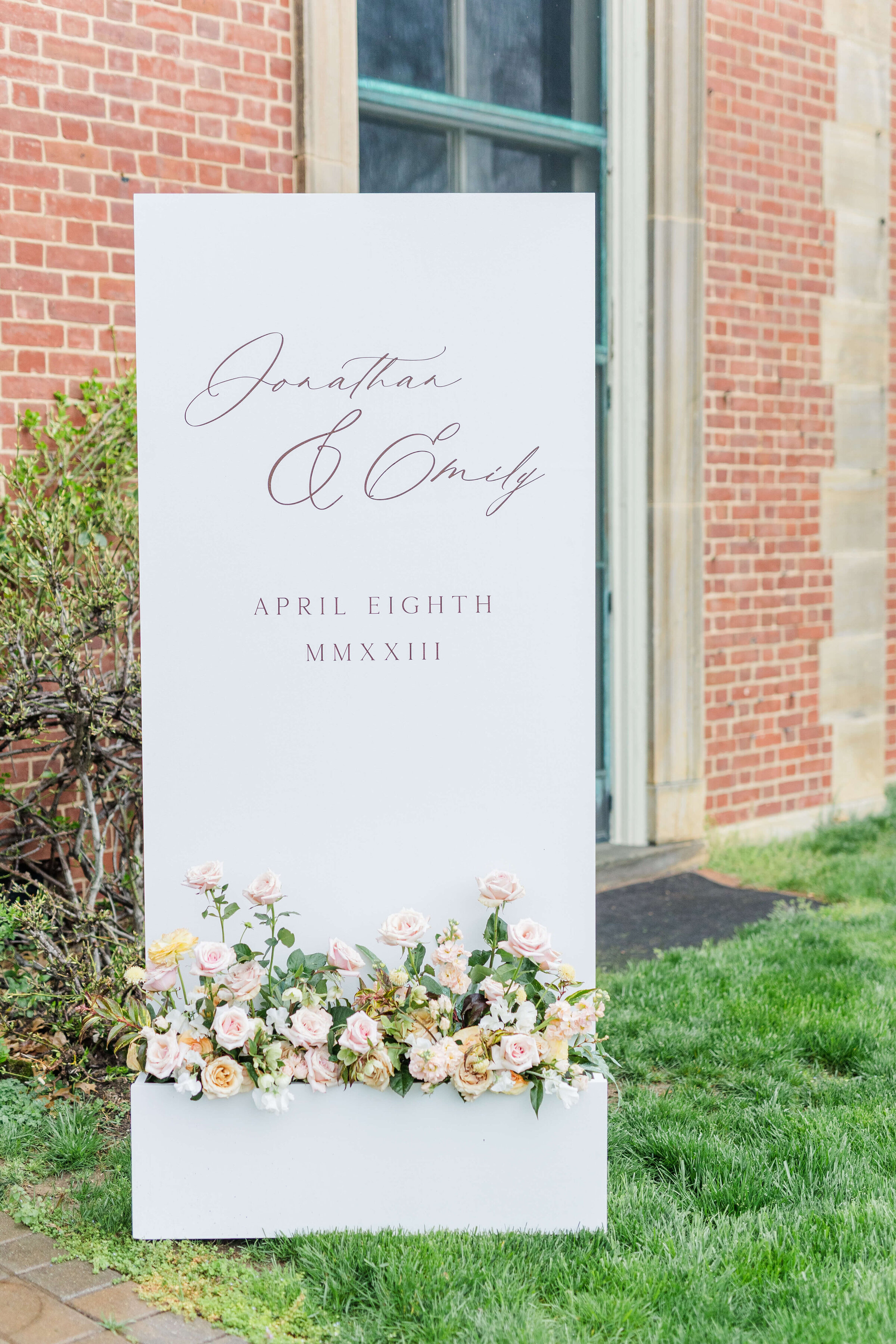A wedding sign that says the bride and groom's name with their wedding date and wedding florals on the bottom of the sign