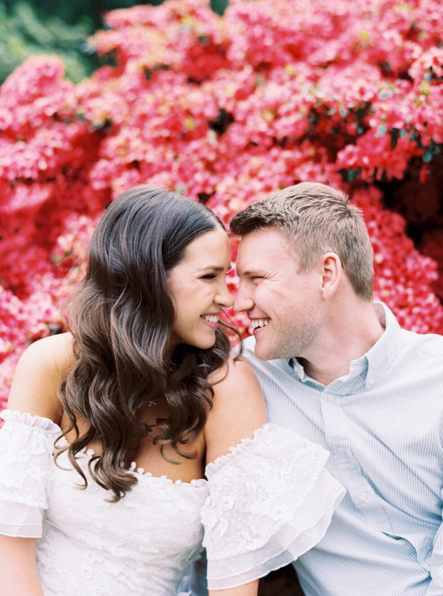 colorful pink azalea's behind couple smiling at each other