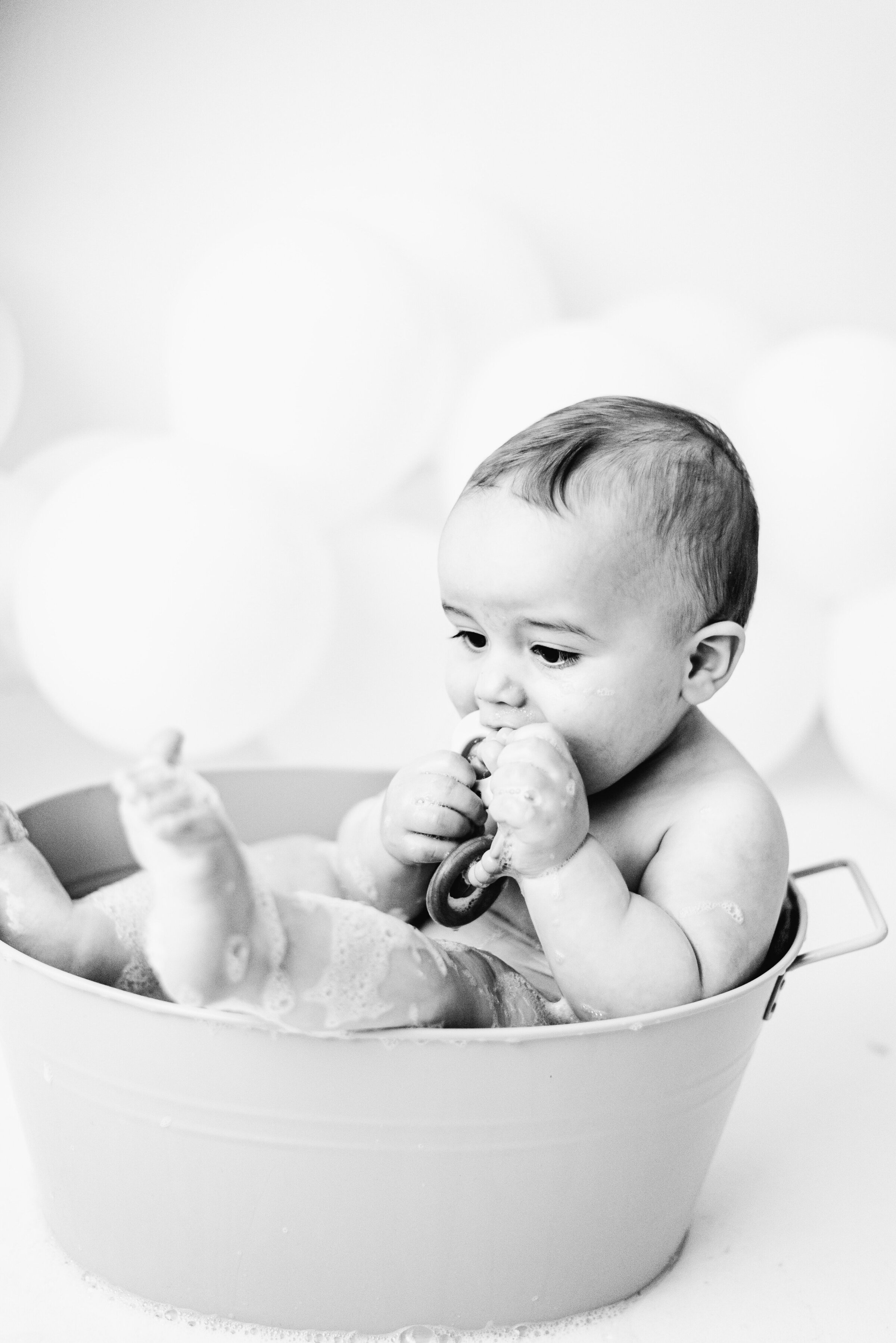 Baby boy sitting in a bath tub with his legs hanging out at cake smash photoshoot in Billingshurst