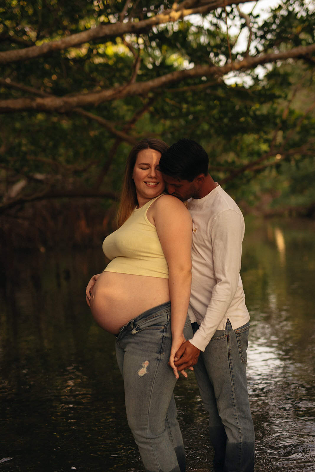 Man kissing pregnant woman by a lake