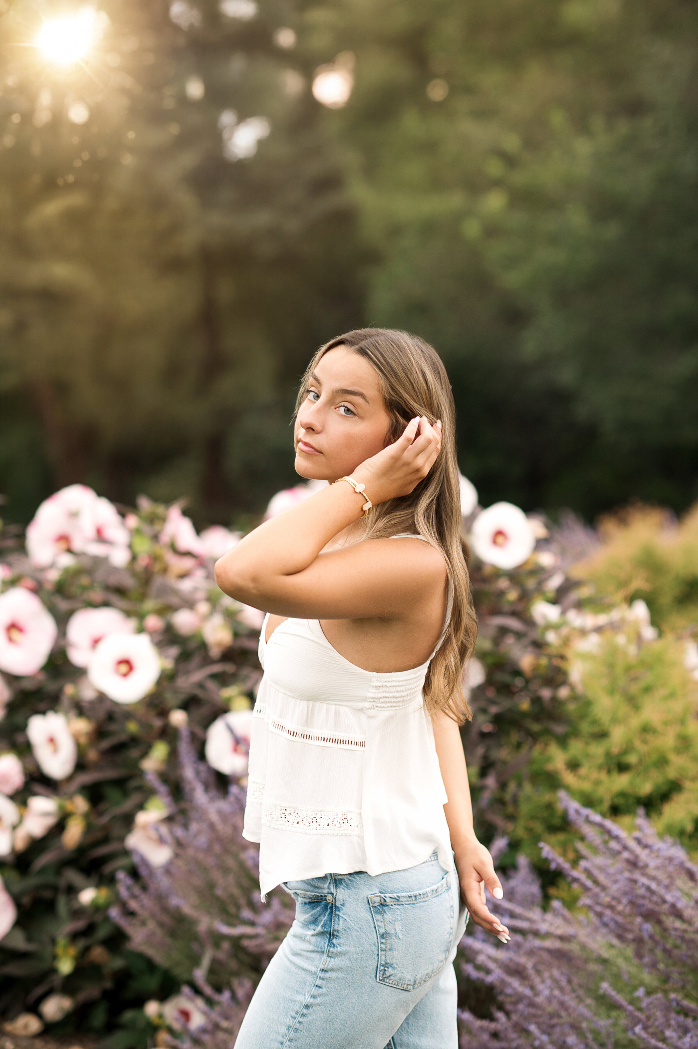 Senior girl in white dress posing in front of pink summer flowers at Hershey Gardens near Lancaster, York, and Harrisburg PA.