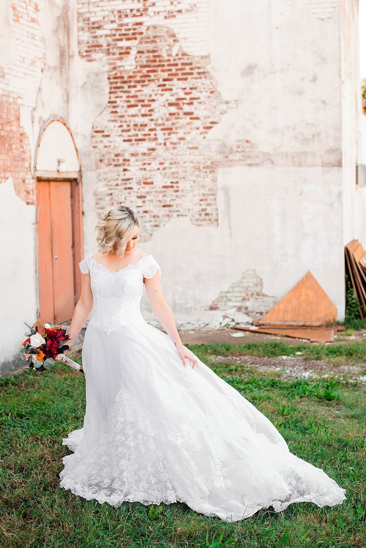 Bride wearing her moms vintage wedding dress in front of white wash brick wall