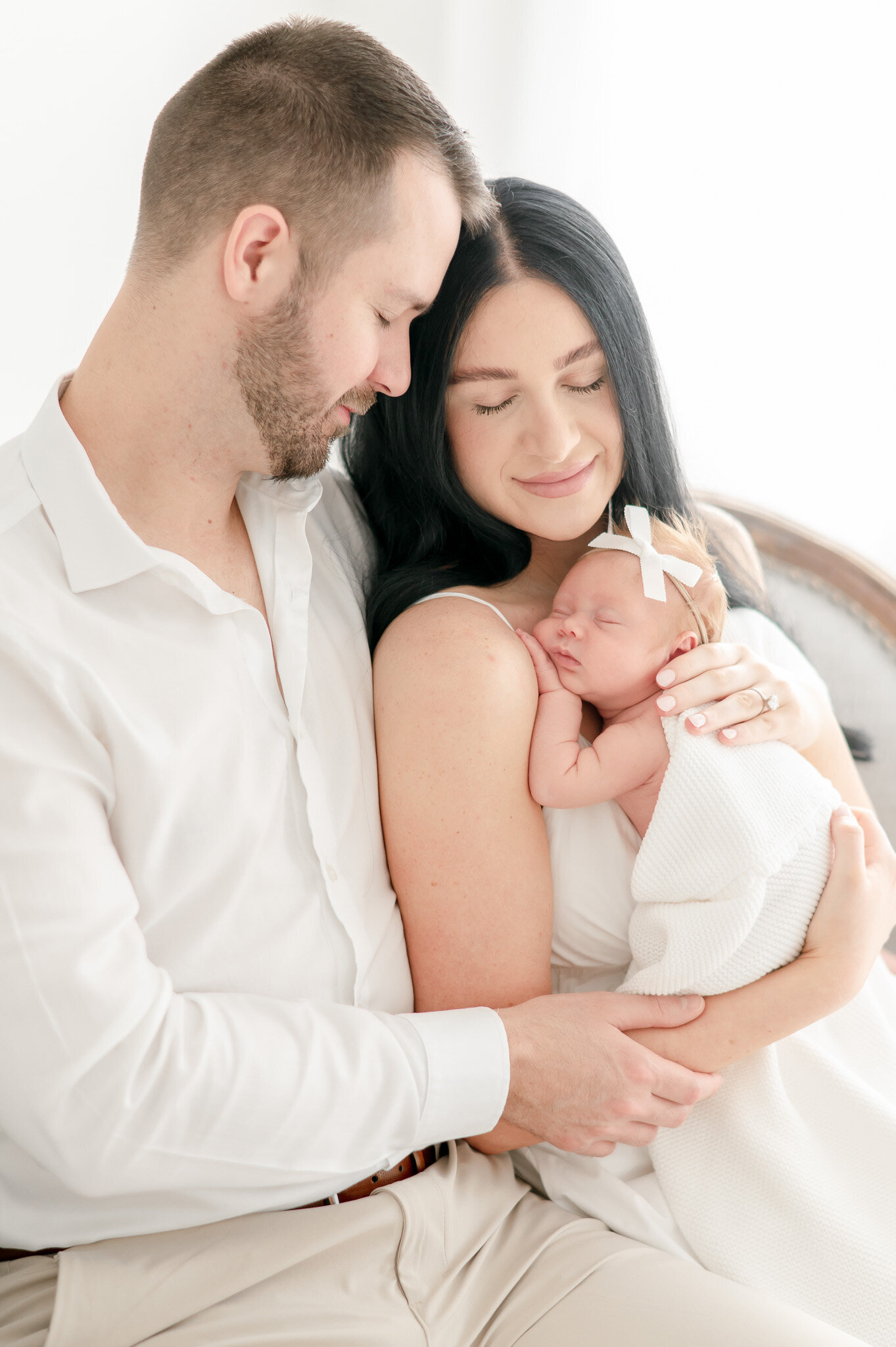a mother and father cuddle their newborn baby  in Kristie Lloyd's Nashville newborn photography studio