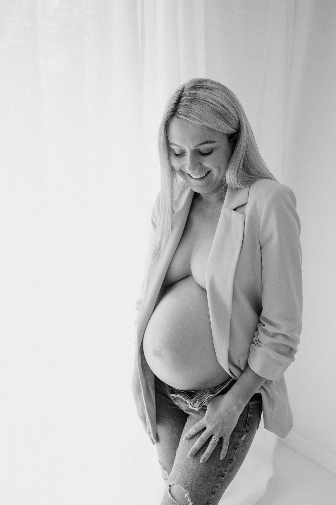 pregnant mum showing her tummy wearing a suit blazer in a beautiful studio