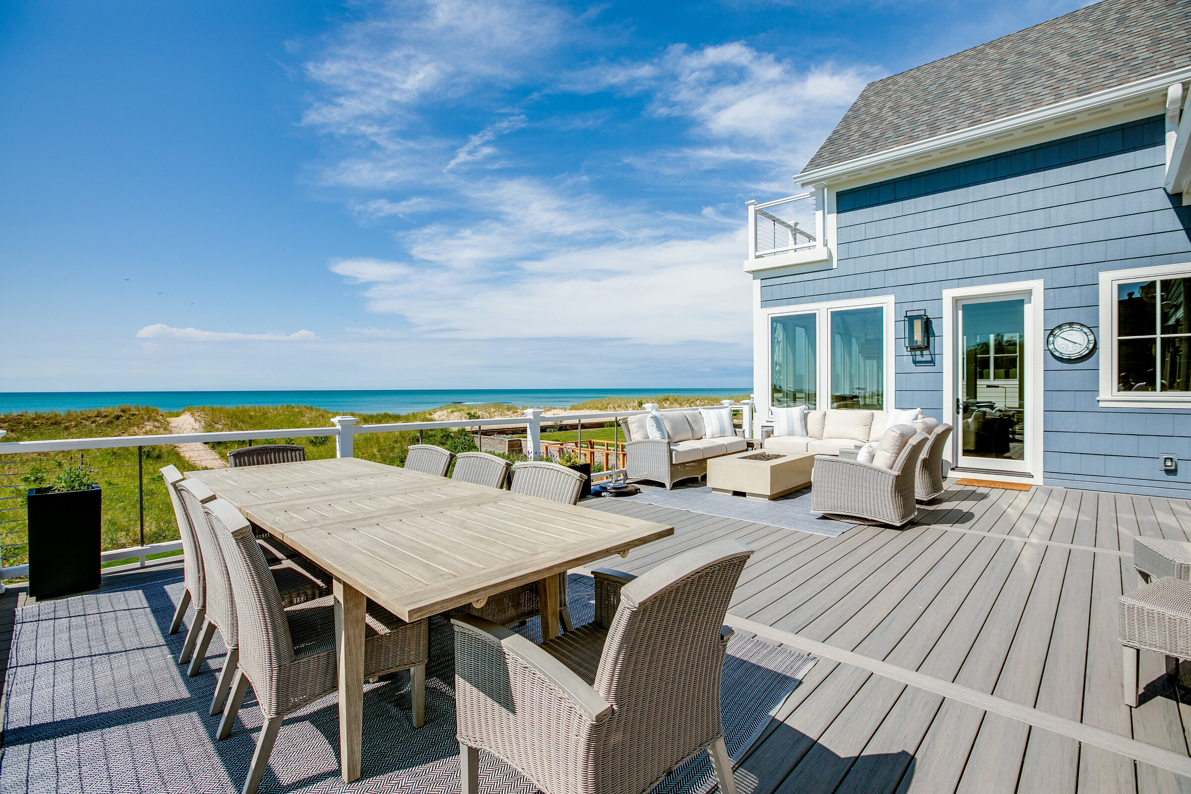 A stunning backyard patio featuring multiple seating areas and a balcony, all overlooking the serene shoreline. The design offers a perfect blend of comfort and breathtaking views, making it an ideal outdoor retreat.