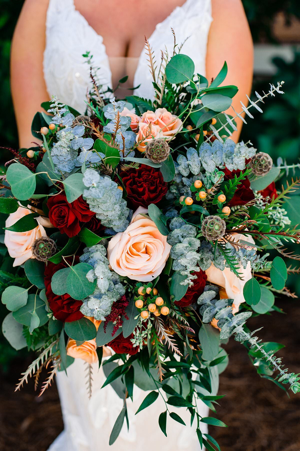 Bride holding large bouquet filled with different types of eucalyptus