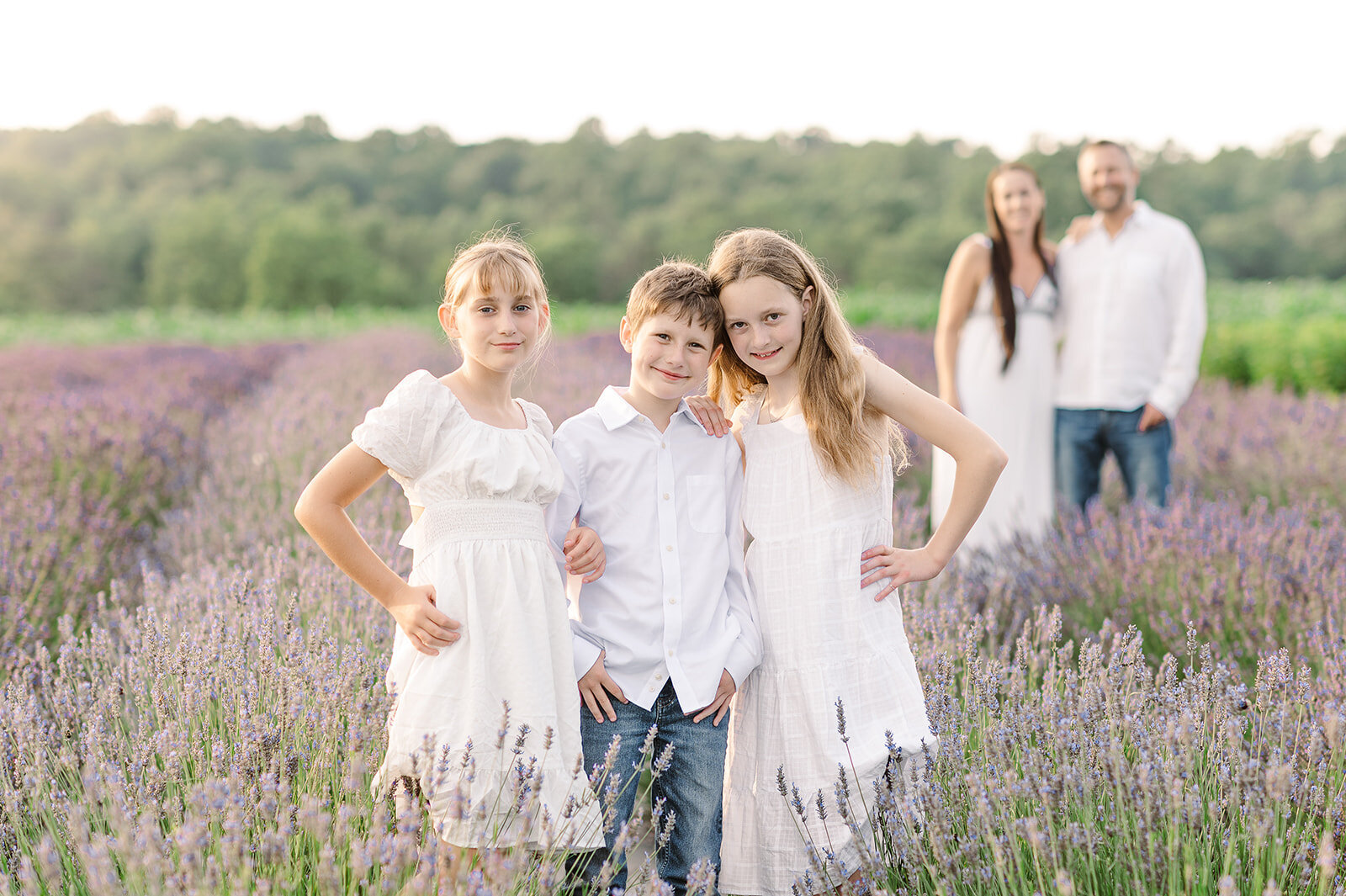 three children standing in lavender field with parents standing behind them baltimore md