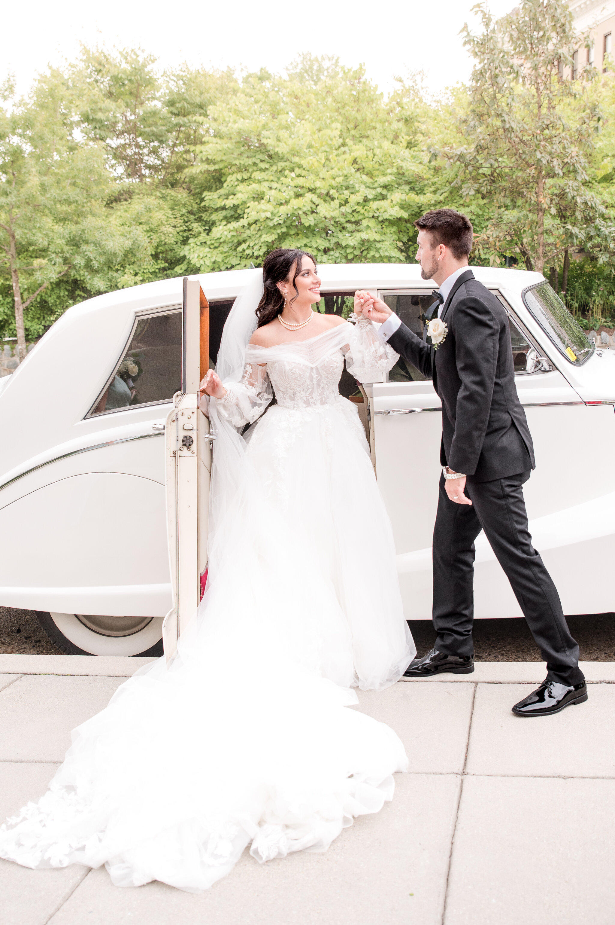 couple holding hands in front of rolls royce on wedding day