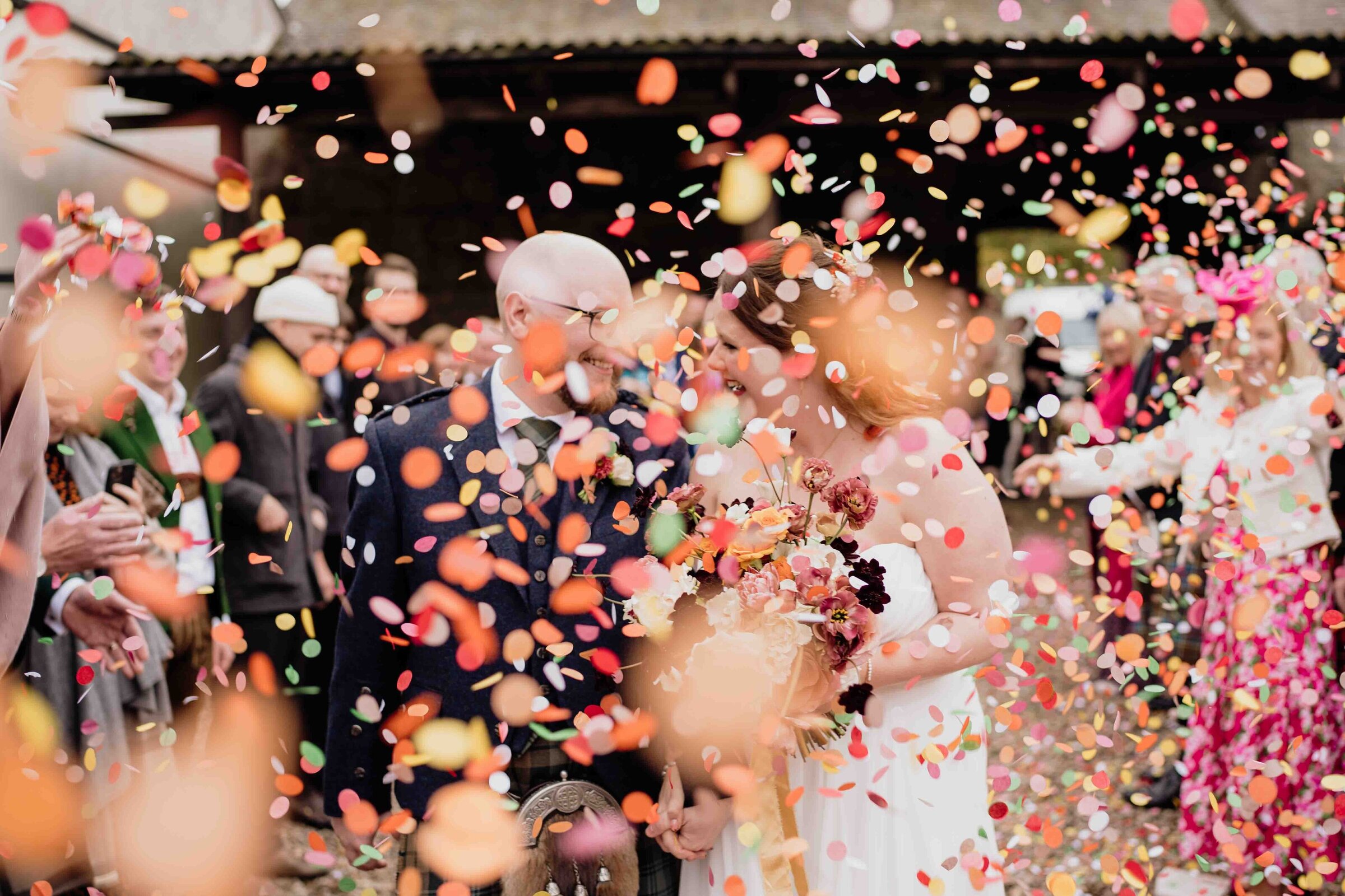 A newly married couple are photographed walking through a confetti tunnel at th Barn at Charleton Farm after their wedding.