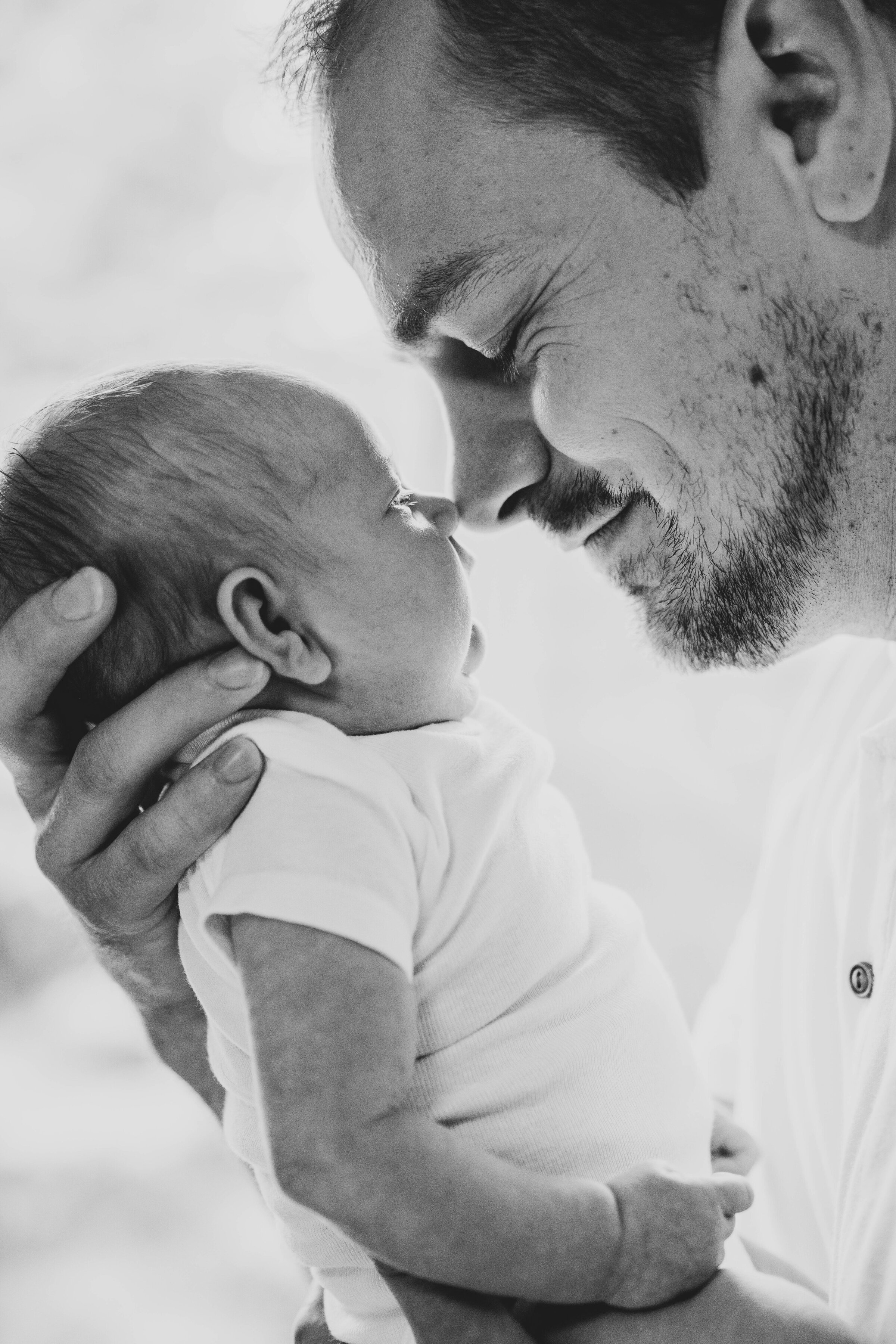 Father touching noses with his newborn baby girl