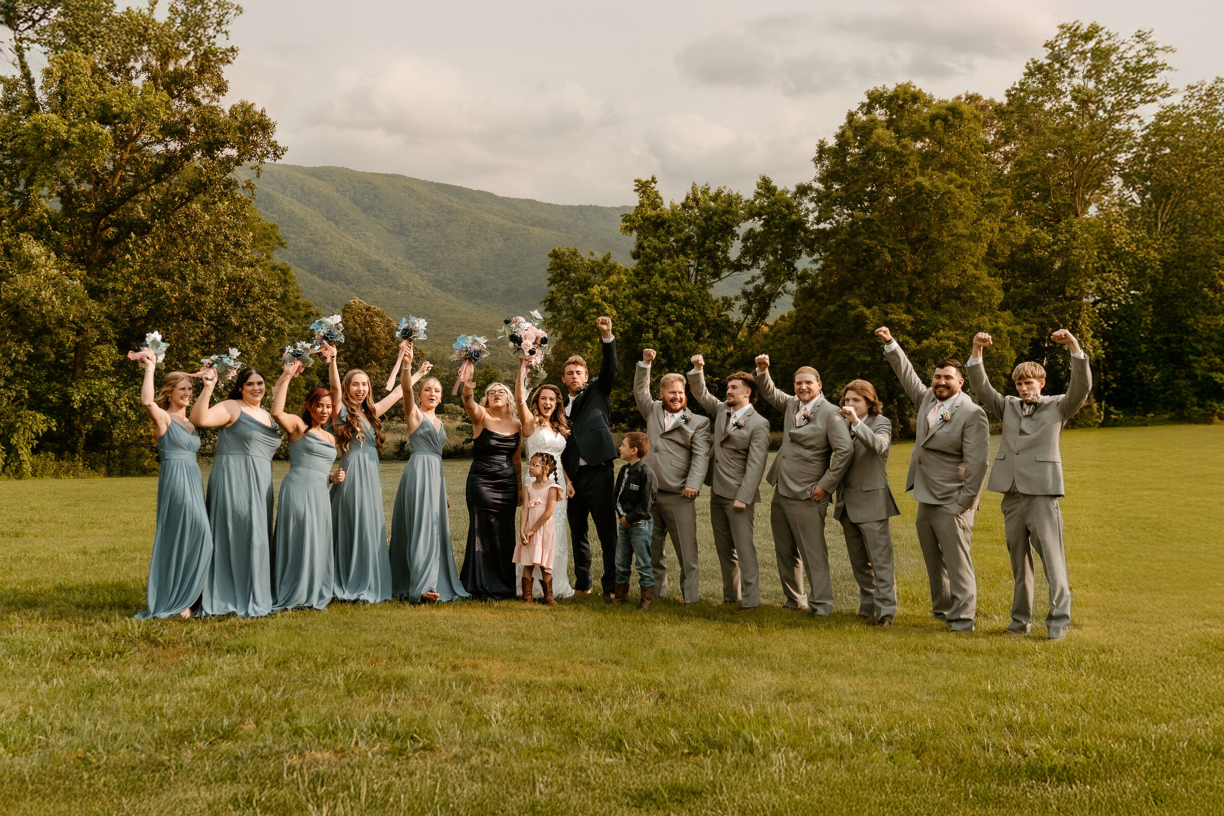 Entire wedding party having fun waving their hands in the air in front of a hazy Applachian mountain scene
