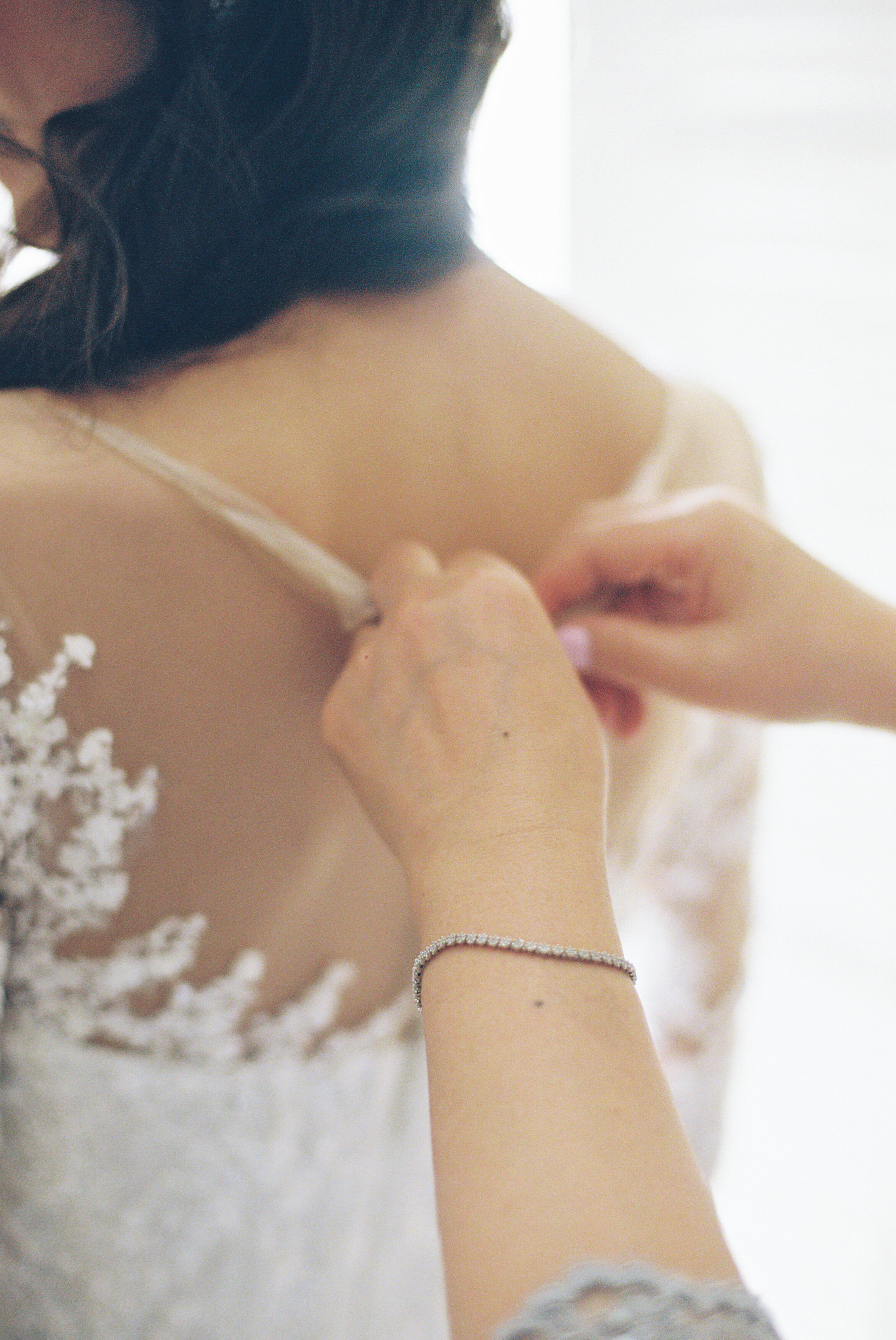 Wedding and Elopement Photographer, someone clasping the back of bride's dress