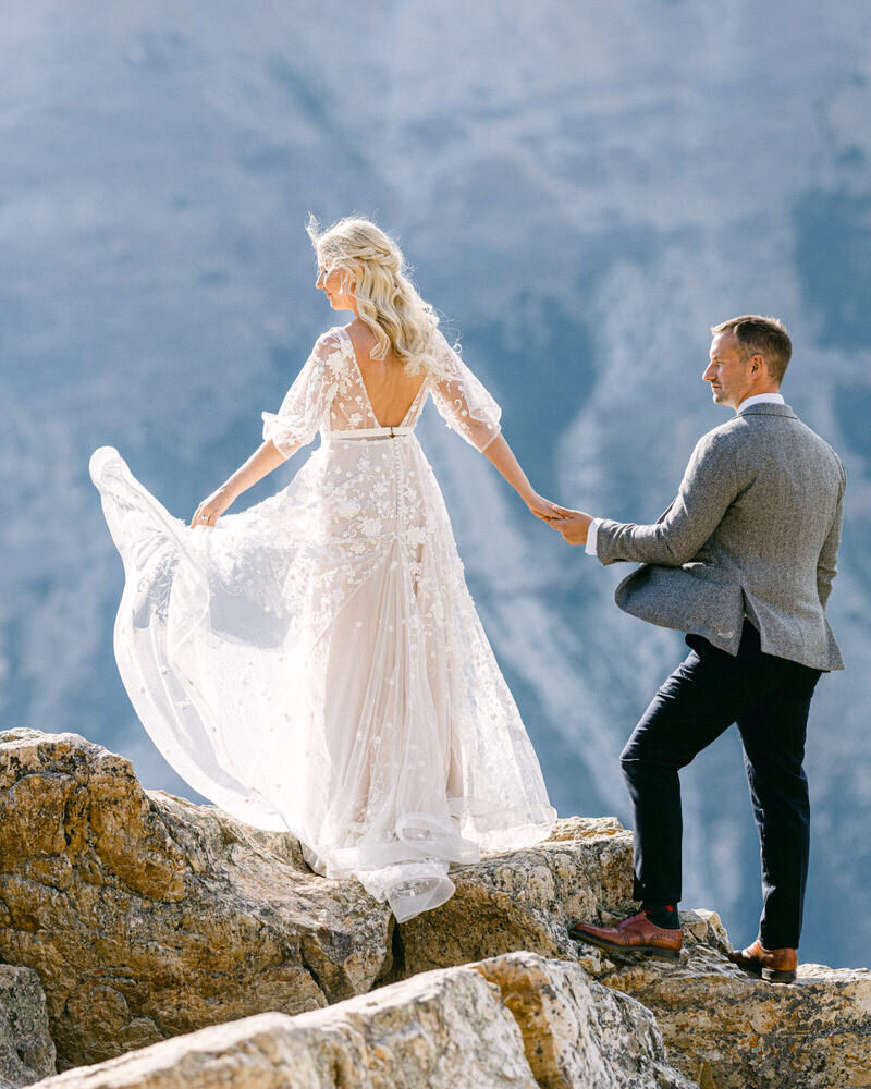 This breathtaking image captures the bride and groom walking hand in hand over boulders at the Peyto Lake viewpoint in Banff National Park. The stunning turquoise waters and rugged landscape create a dramatic backdrop, enhancing the adventurous spirit of their wedding day.