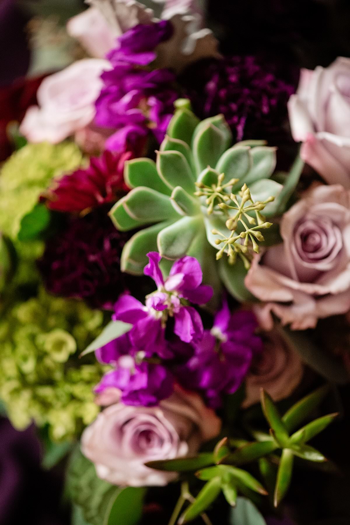 Detail photo of purple, pink and succulents in a bride bouquet