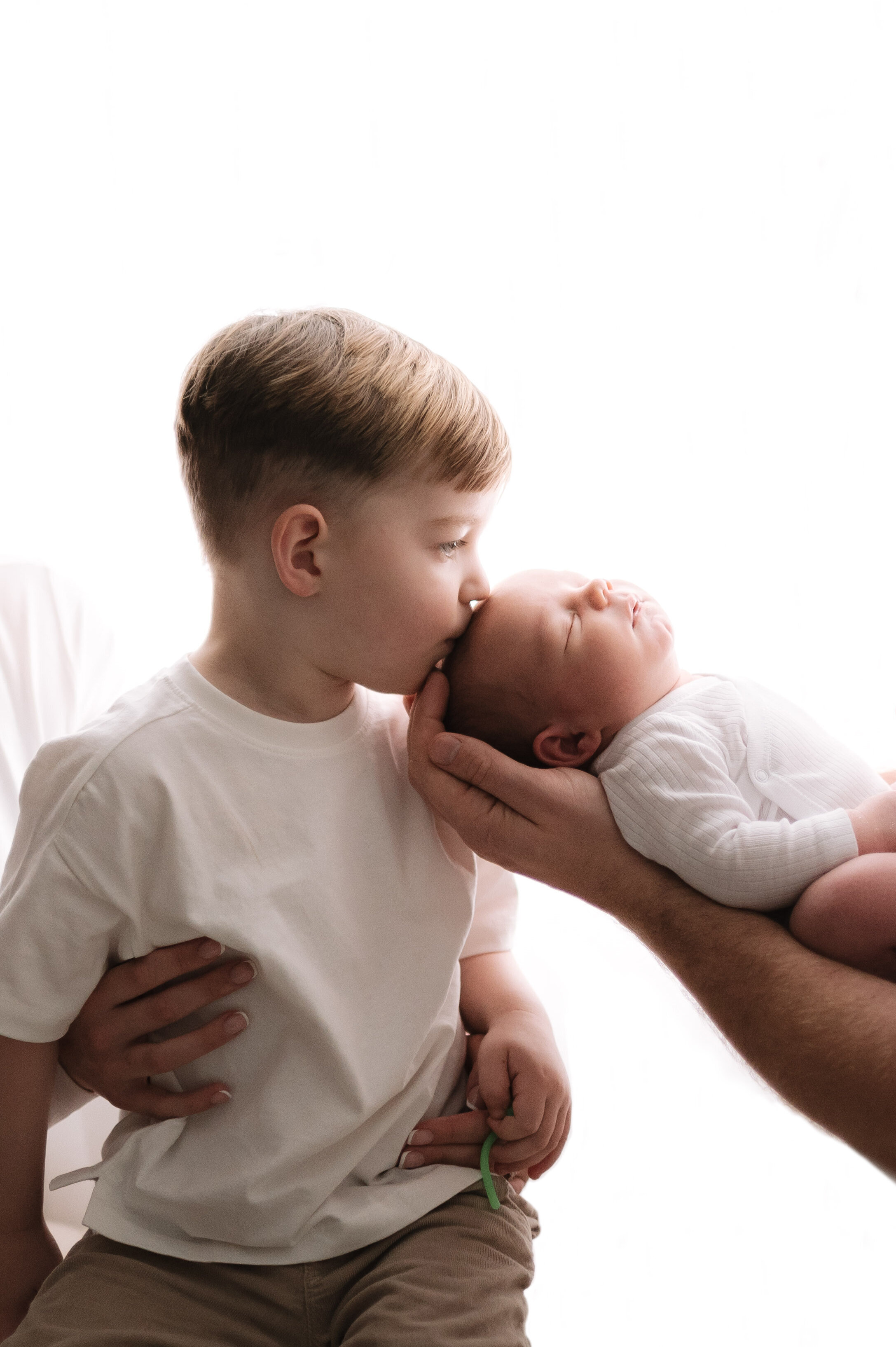 Big brother kissing his newborn brothers head at Billingshurst newborn photoshoot