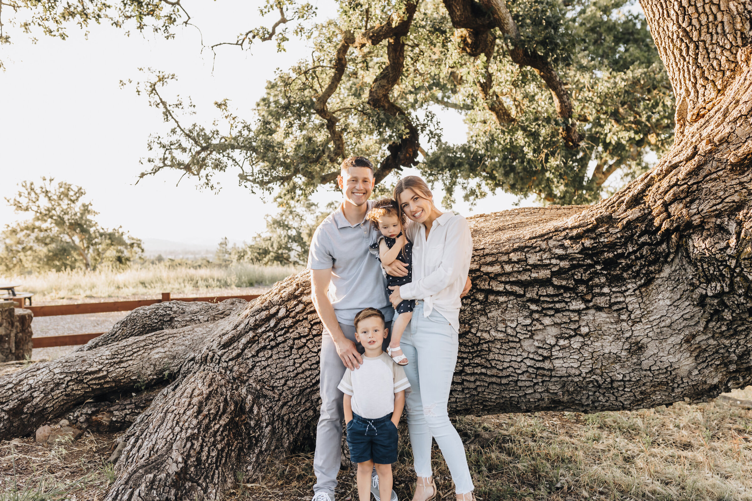 Family nestles under a big tree at the park