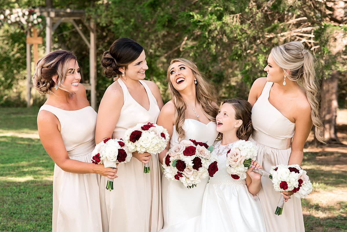 Bridesmaids wearing pale pink dresses holding light colored flowers with burgundy, pink and creams