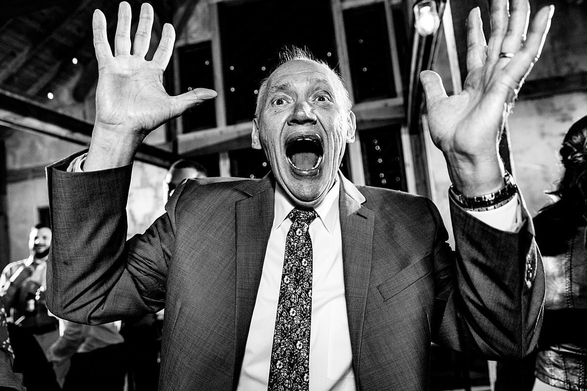 Black and White photo of grandpa excited with hands in the air dancing on dance floor