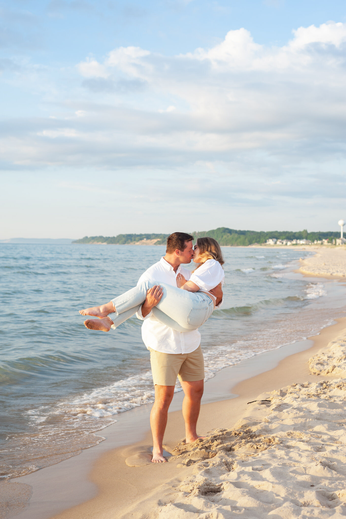 man holding his girl and kissing her at a beach sunset